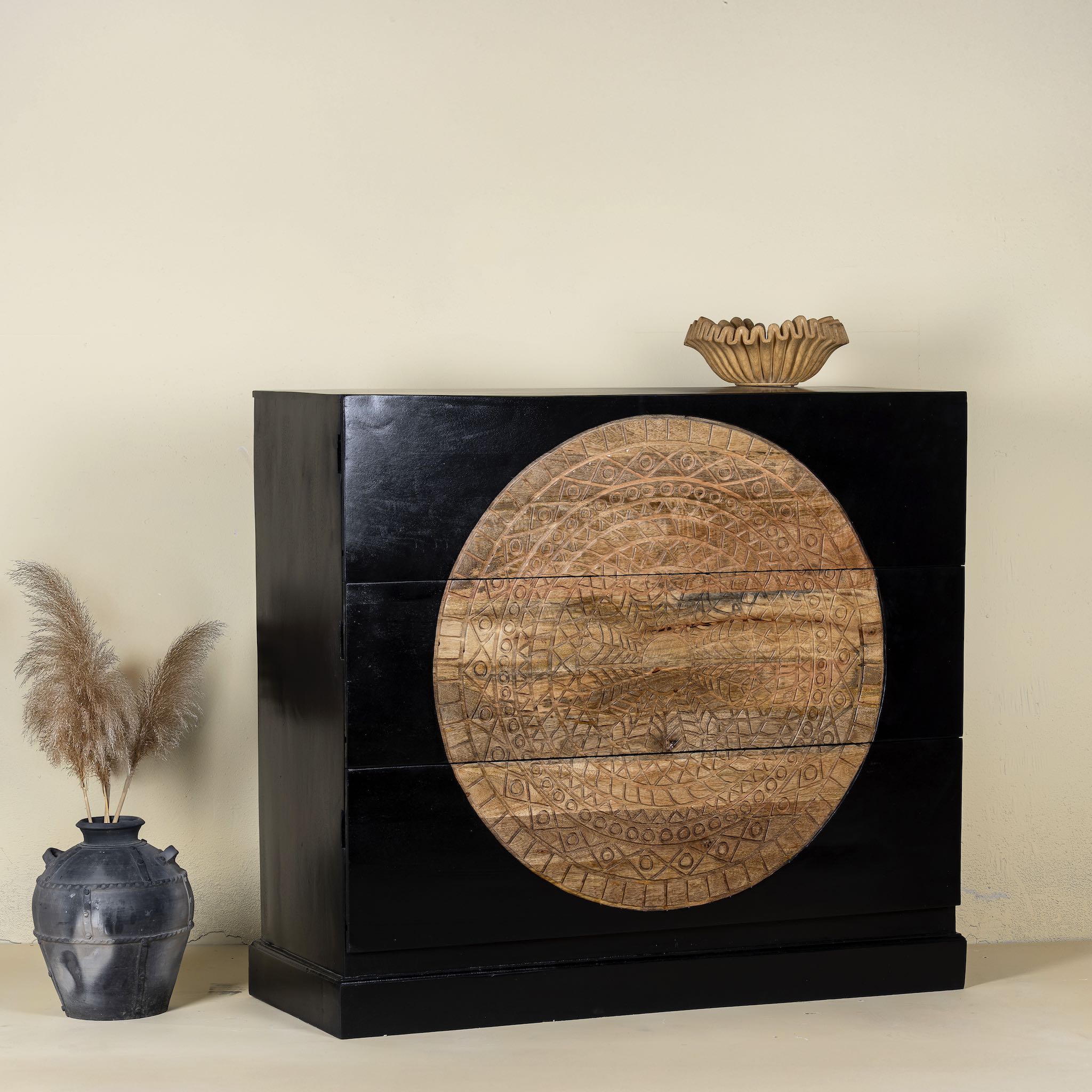 Side angle image of a mandala carved wood chest with black frame and natural carved mango wood drawers, mango wood drawer chest for modern bohemian interiors, 120 × 47 × 110 cm.