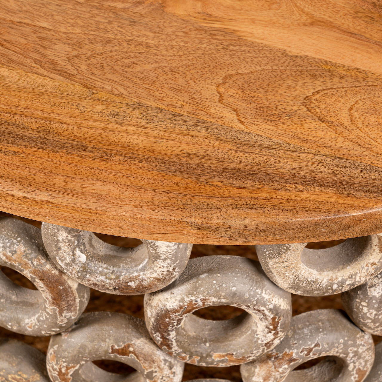 Close up image of a round mango wood coffee table with carved base and natural top; vintage living room furniture, 77 cm diameter × 44 cm height.