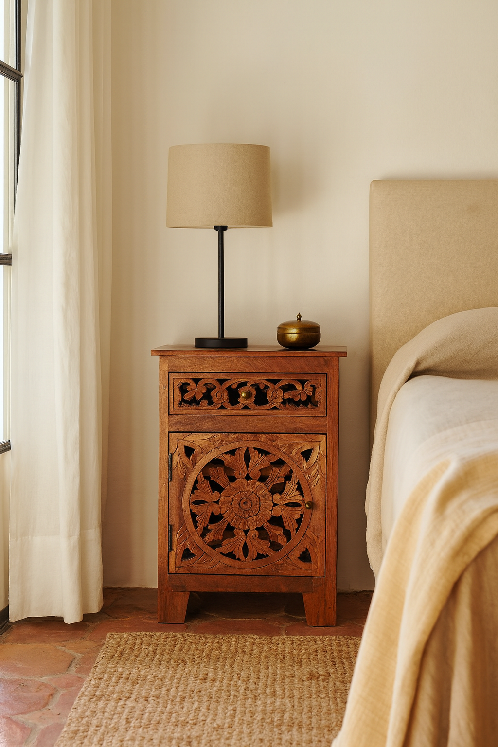 Lifestyle scene with a pair of mango wood night stands with hand carved floral and geometric detailing, warm teak finish; elegant hand carved furniture, 45 × 35 × 65 cm.