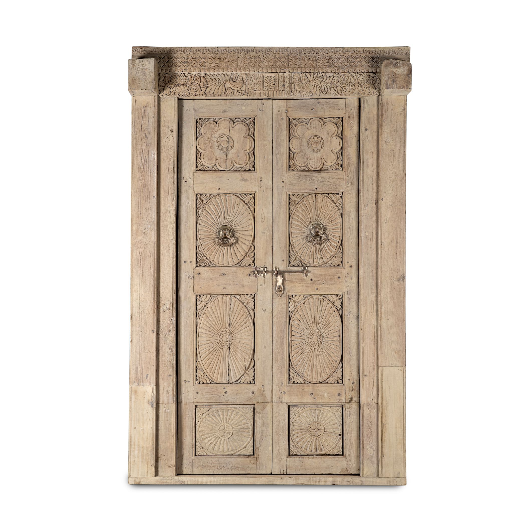 White background image of an antique Indian door Akshara in reclaimed teak with brass locks, hand-carved details, extended frame, unique furniture and vintage wall panels, 148 × 30 × 225 cm.