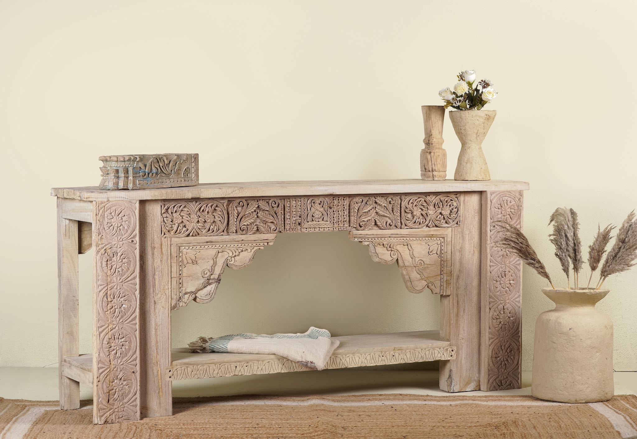 Side angle image of a antique teak console table made from reclaimed wood with hand-carved floral and geometric panels, 183 × 40 × 82 cm.
