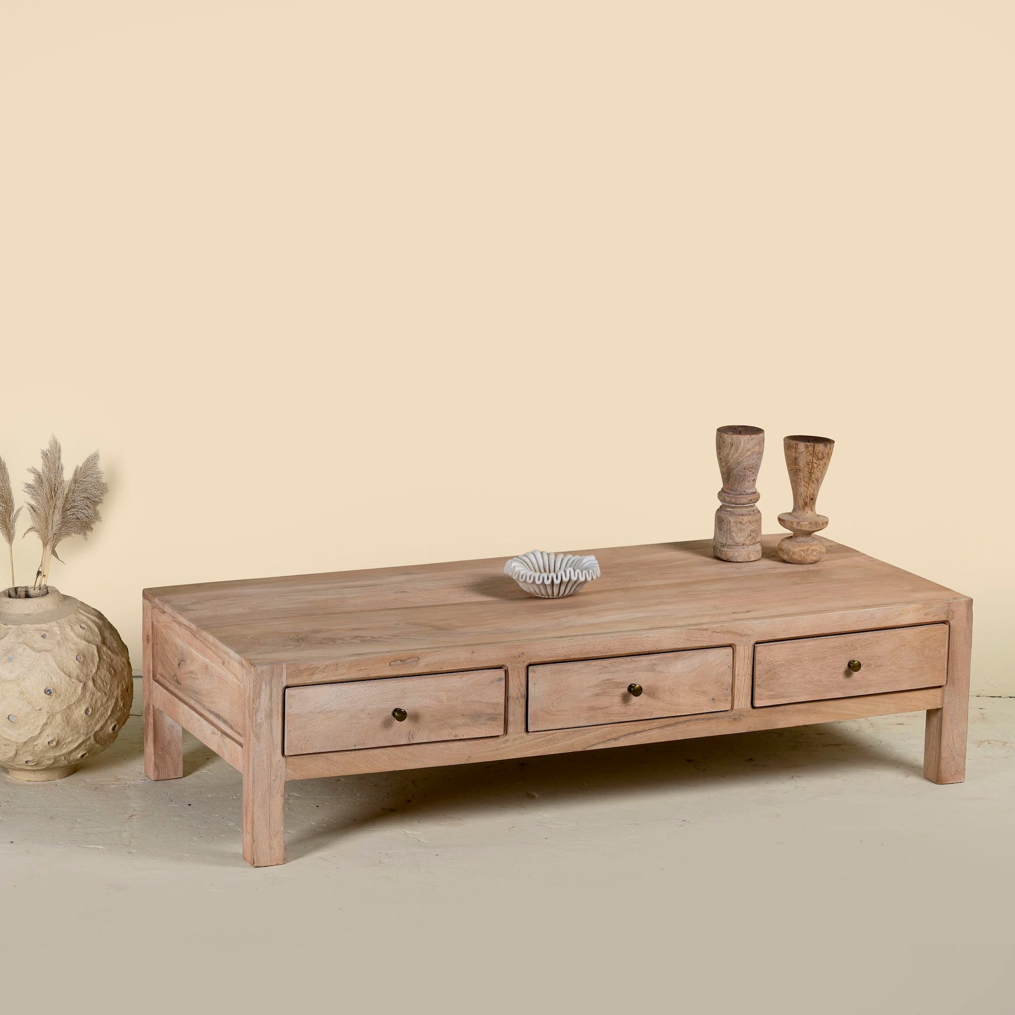 Side angle image of a minimalistic wooden coffee table made from reclaimed wood with three drawers; natural finish, 150 × 60 × 45 cm.