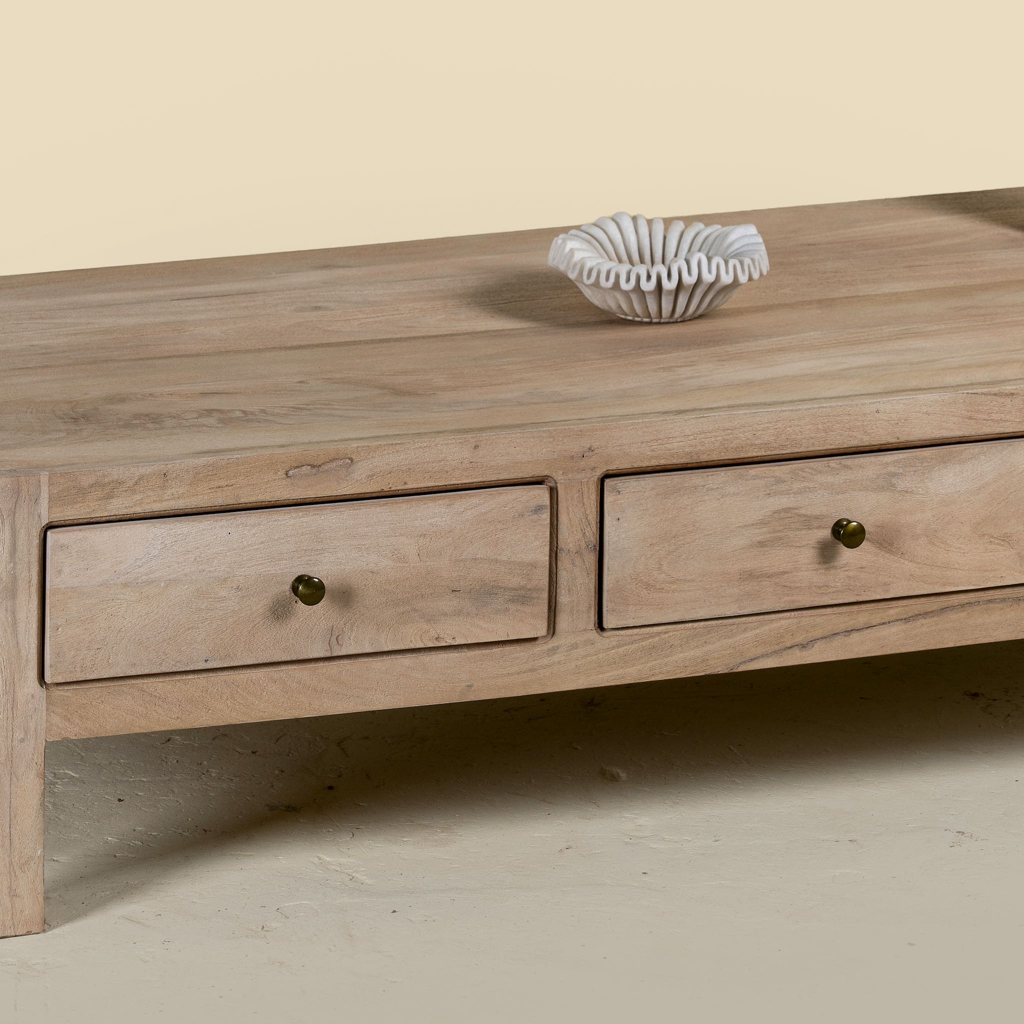 Close up image of a minimalistic wooden coffee table made from reclaimed wood with three drawers; natural finish, 150 × 60 × 45 cm.