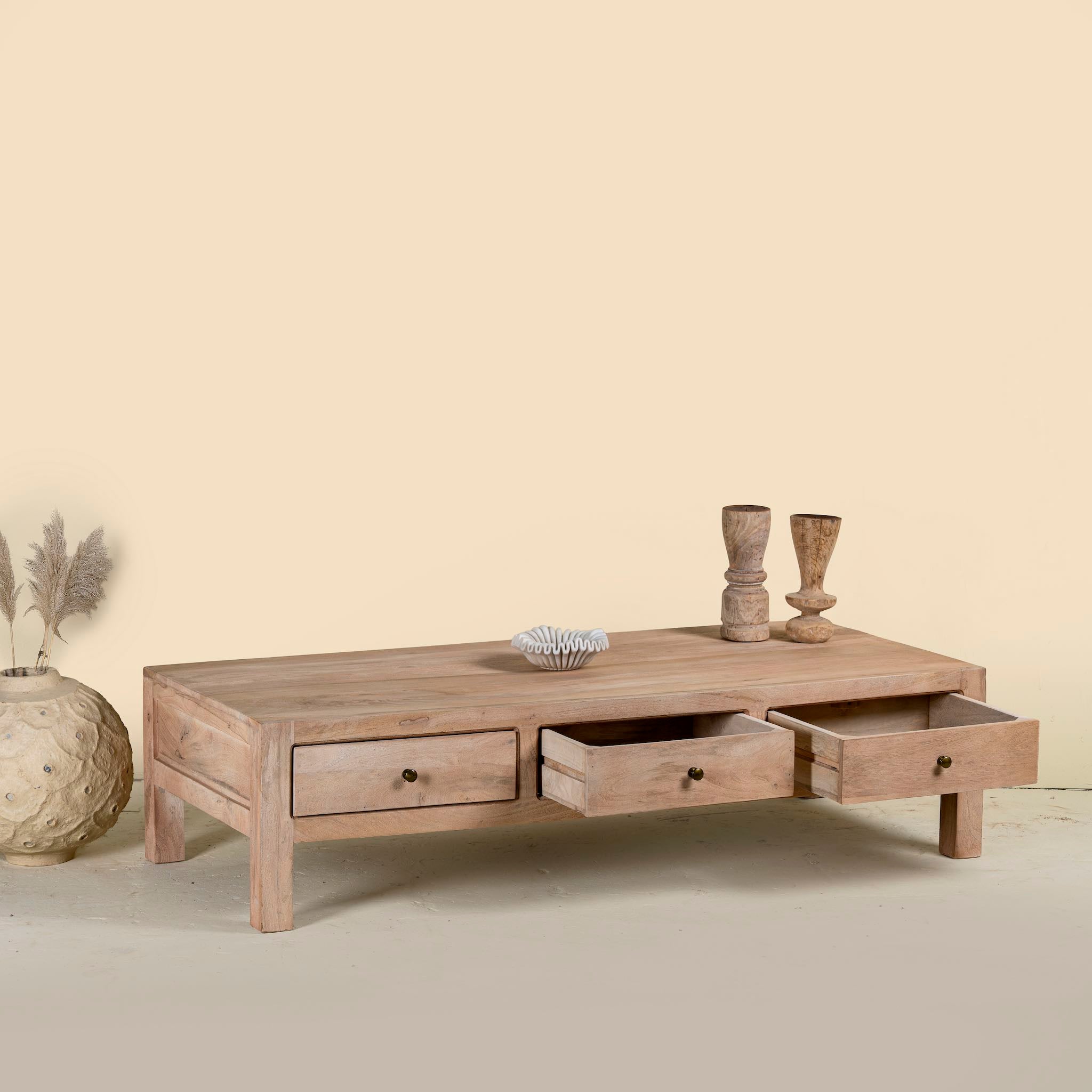 Side angle image with open drawers of a minimalistic wooden coffee table made from reclaimed wood with three drawers; natural finish, 150 × 60 × 45 cm.