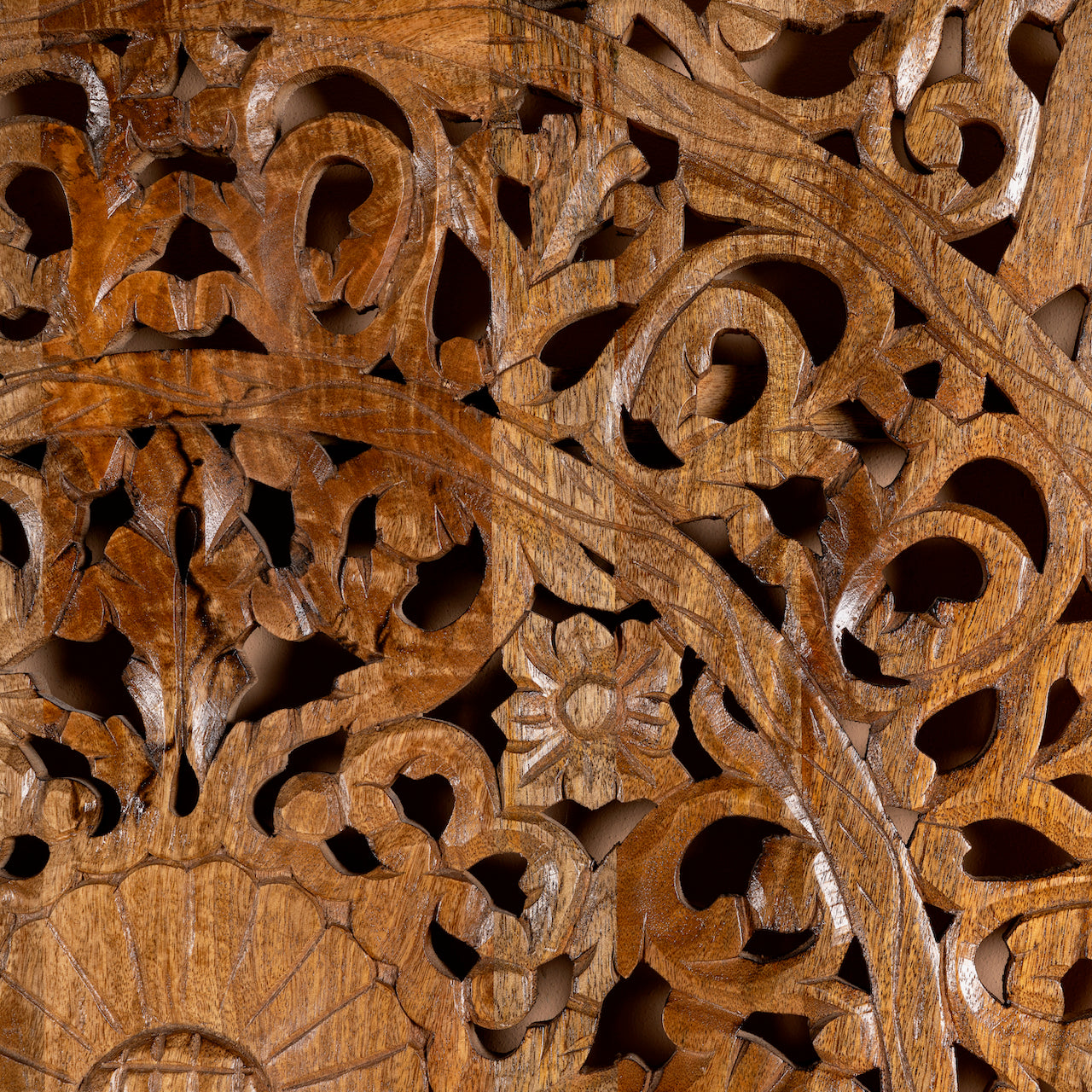 Close up image of a hand-carved mango wood wall panel in natural finish with floral designs – Asamanja model by Om Home & Garden