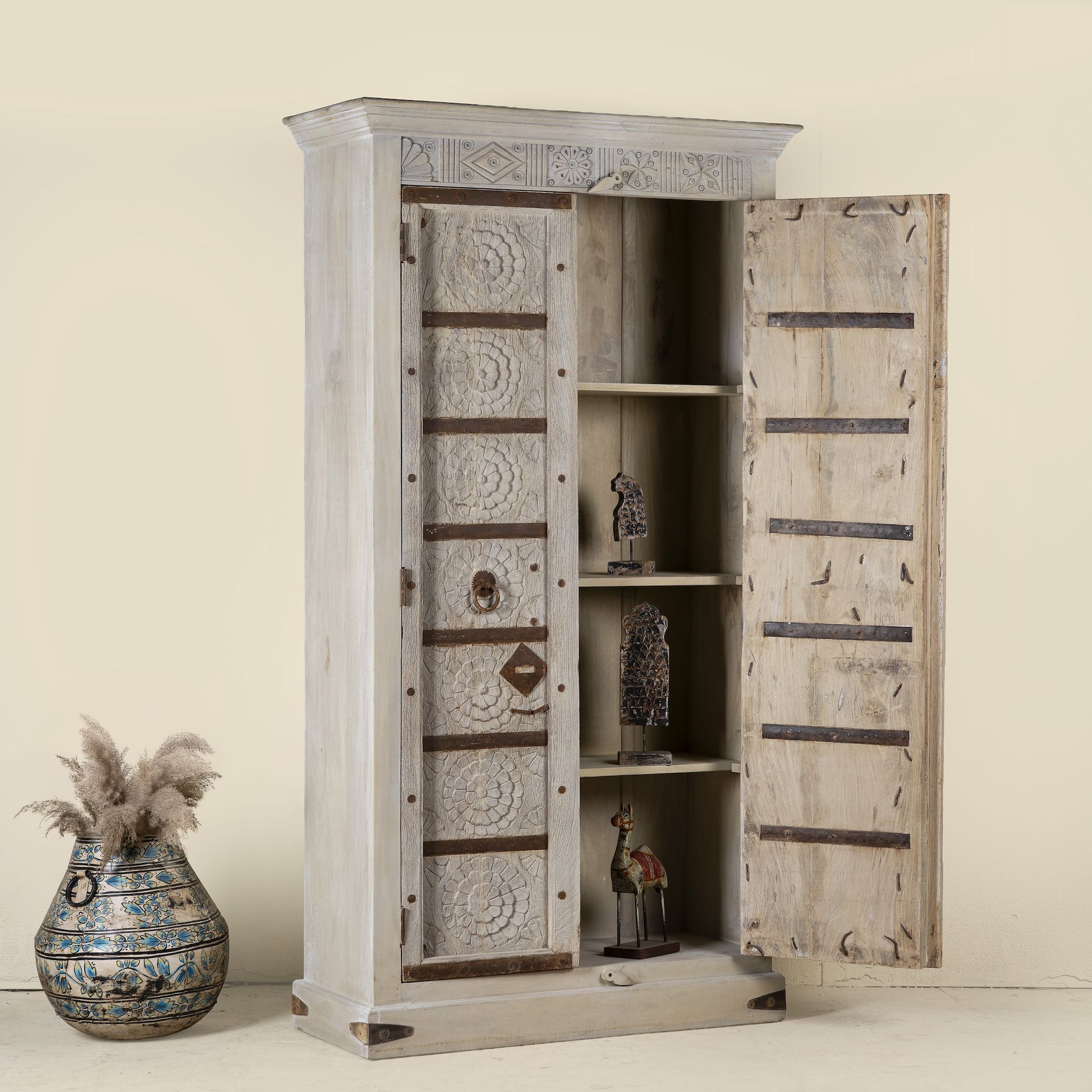 Open door image of a old door cabinet with reclaimed teak doors, floral carvings, and iron accents; artisan teak wood wardrobe with mango wood frame, 100 × 44 × 206 cm.