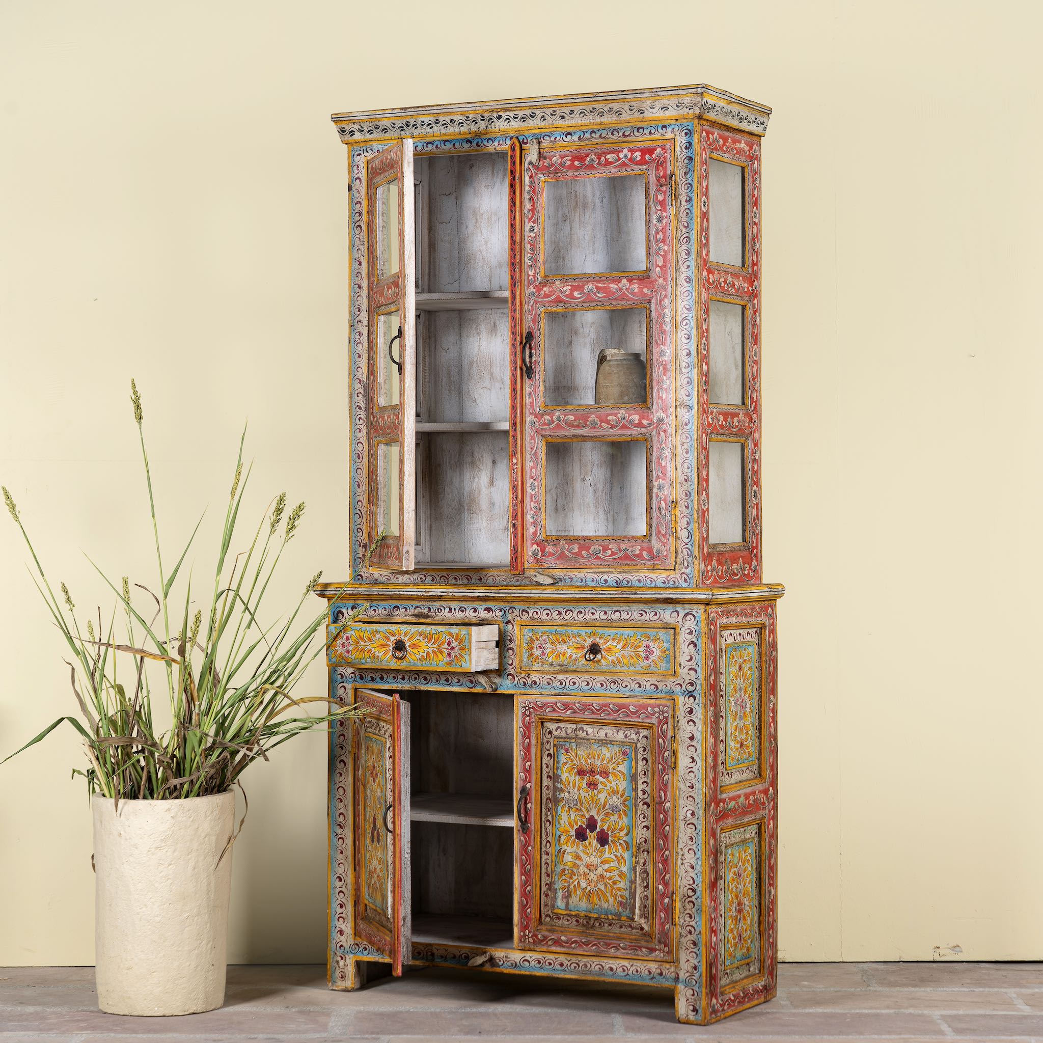 Sde angle image with open drawers of a hand-painted two-part showcase made of reclaimed wood with floral motifs; unique furniture for a boho chic living room, 94 × 48 × 203 cm.