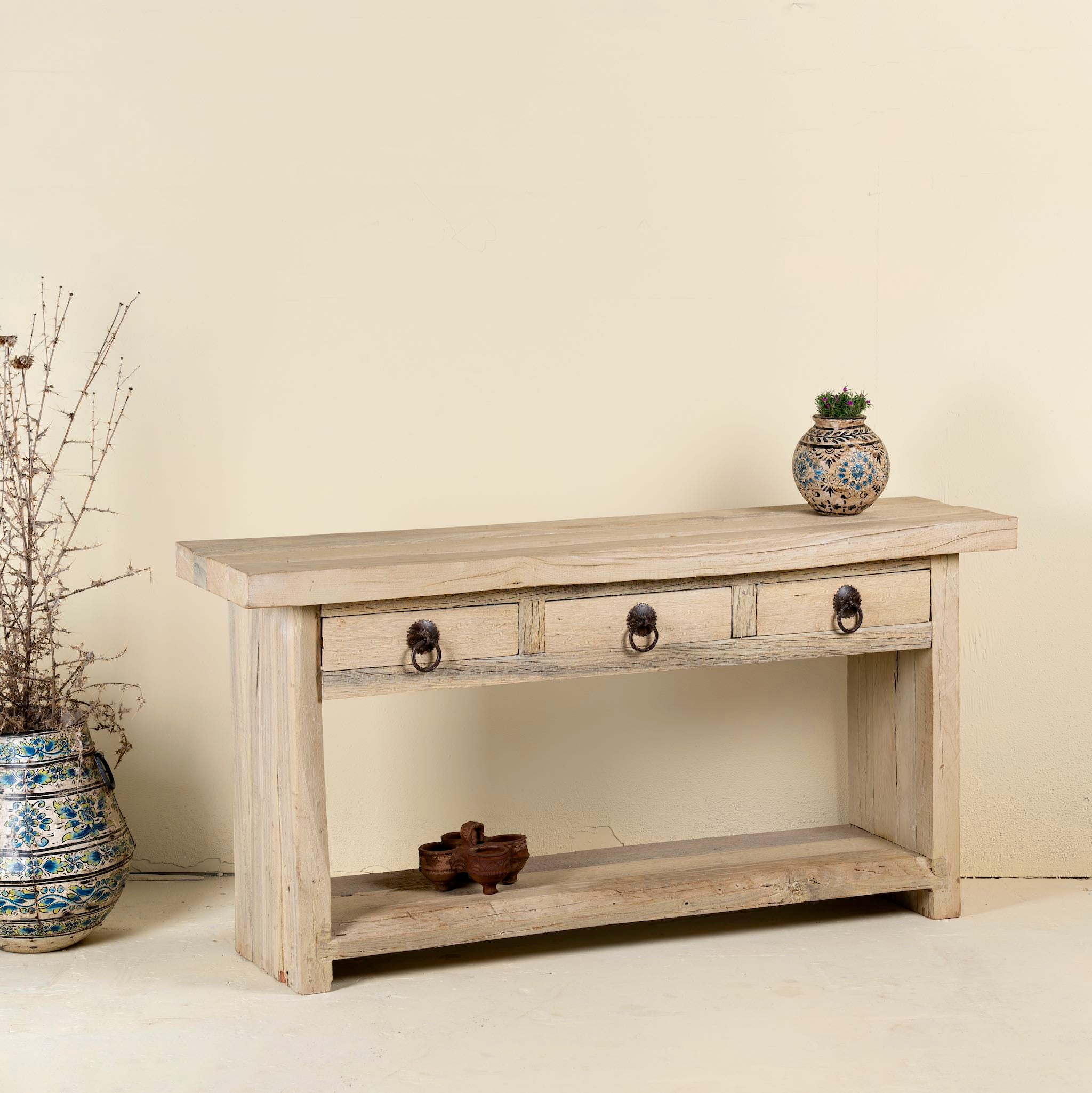Side angle image of a teak wood console table with sandblasted finish, three drawers and lower shelf; sustainable furniture for entryways, living rooms, or bathrooms, 160 × 30 × 80 cm.