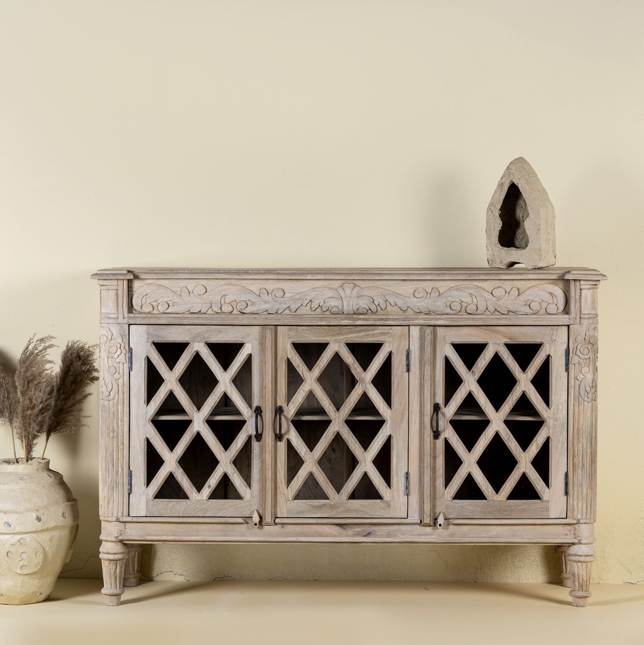 Rustic sideboard made of Mango wood with hand-carved details and glass panelled doors featuring a diamond lattice design.