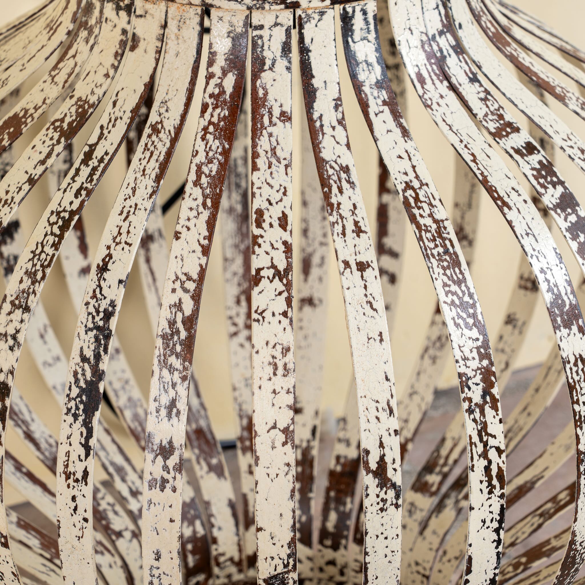 Close up image of a Daiwik whitewashed metal pendant light with sculptural openwork lantern design and iron chain—an eye-catching example of hand crafted metal lamps and artisan metal pendant lights.