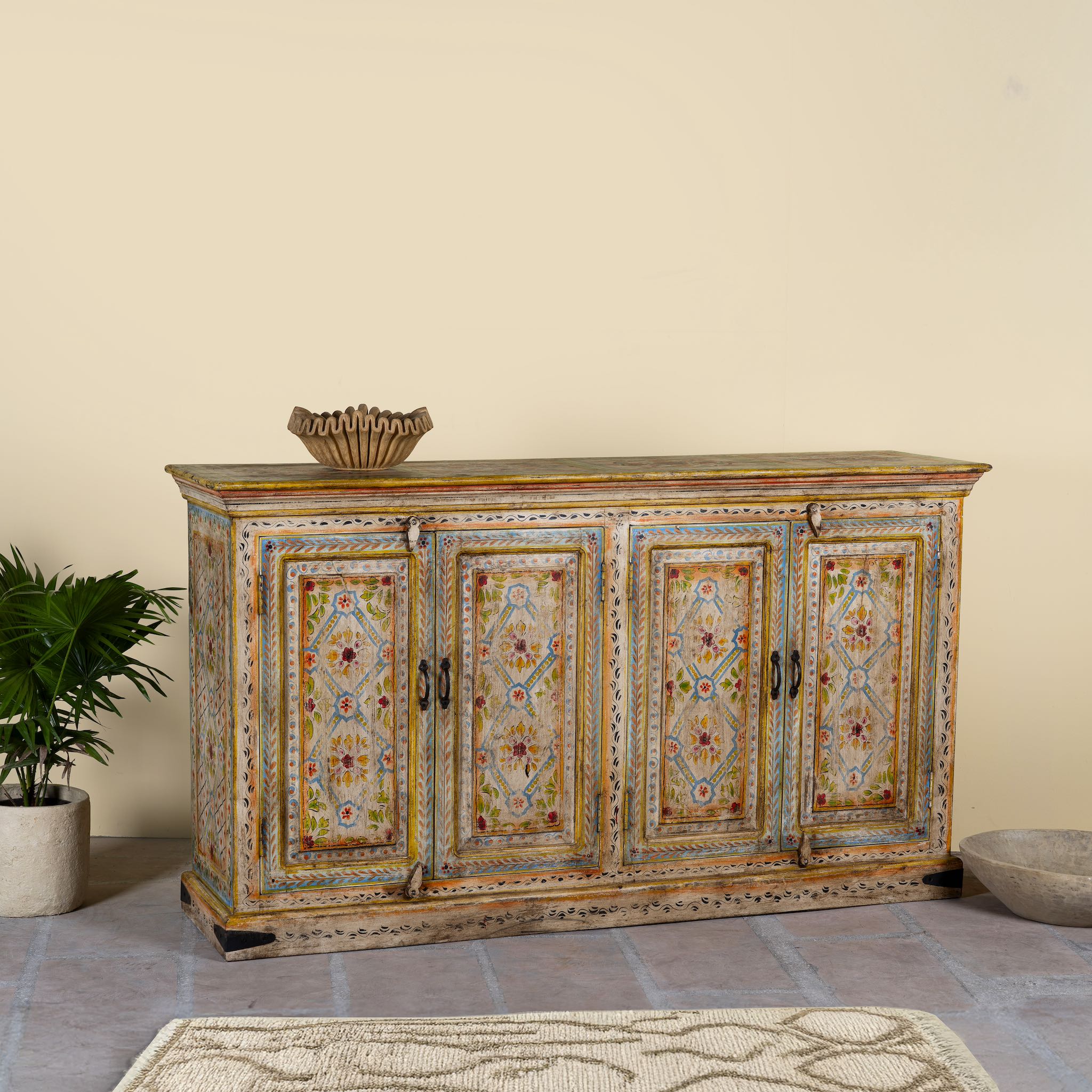 Side angle image of a hand-painted reclaimed wood sideboard with floral motifs, a bold piece of vintage furniture for living room furniture collections.