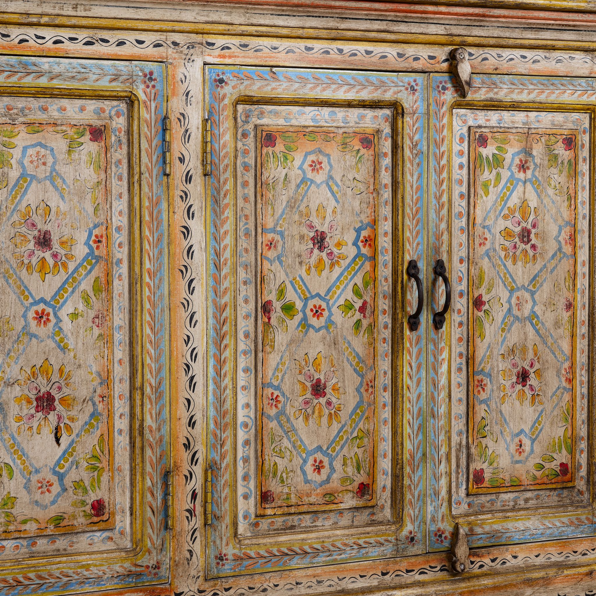Close up image of a hand-painted reclaimed wood sideboard with floral motifs, a bold piece of vintage furniture for living room furniture collections.
