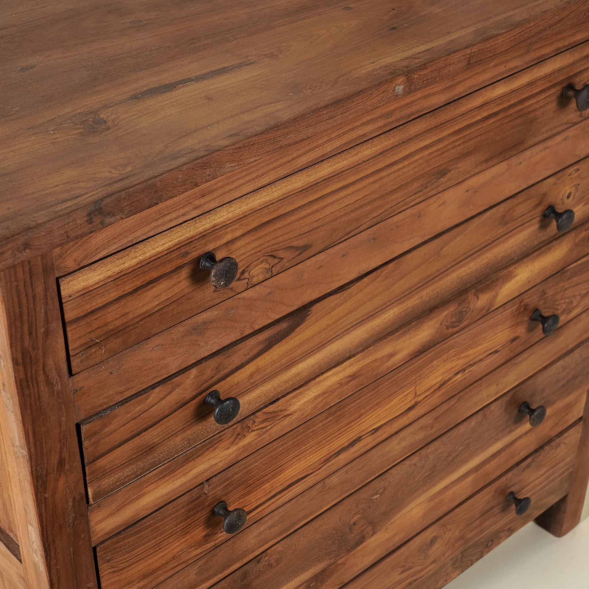 Close up picture of a chest of drawers made from reclaimed teak wood, featuring a minimalist design with five spacious drawers and a warm natural finish- ideal for rustic and modern interiors.