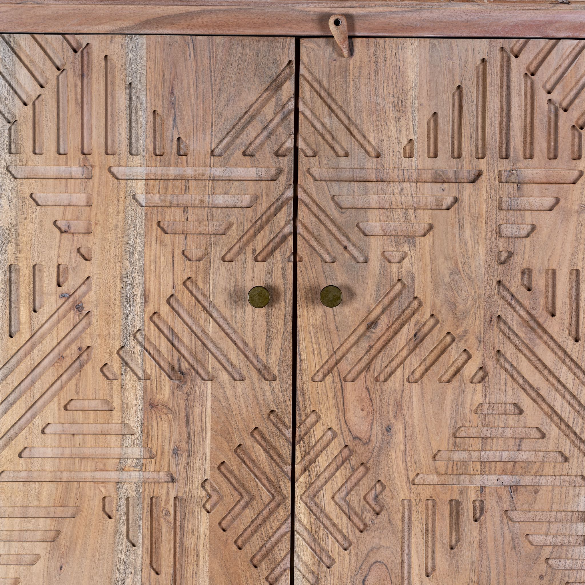 Close up view of a hand crafted acacia wood cabinet with 4 doors, brass fitted door knobs and geometrical carvings.