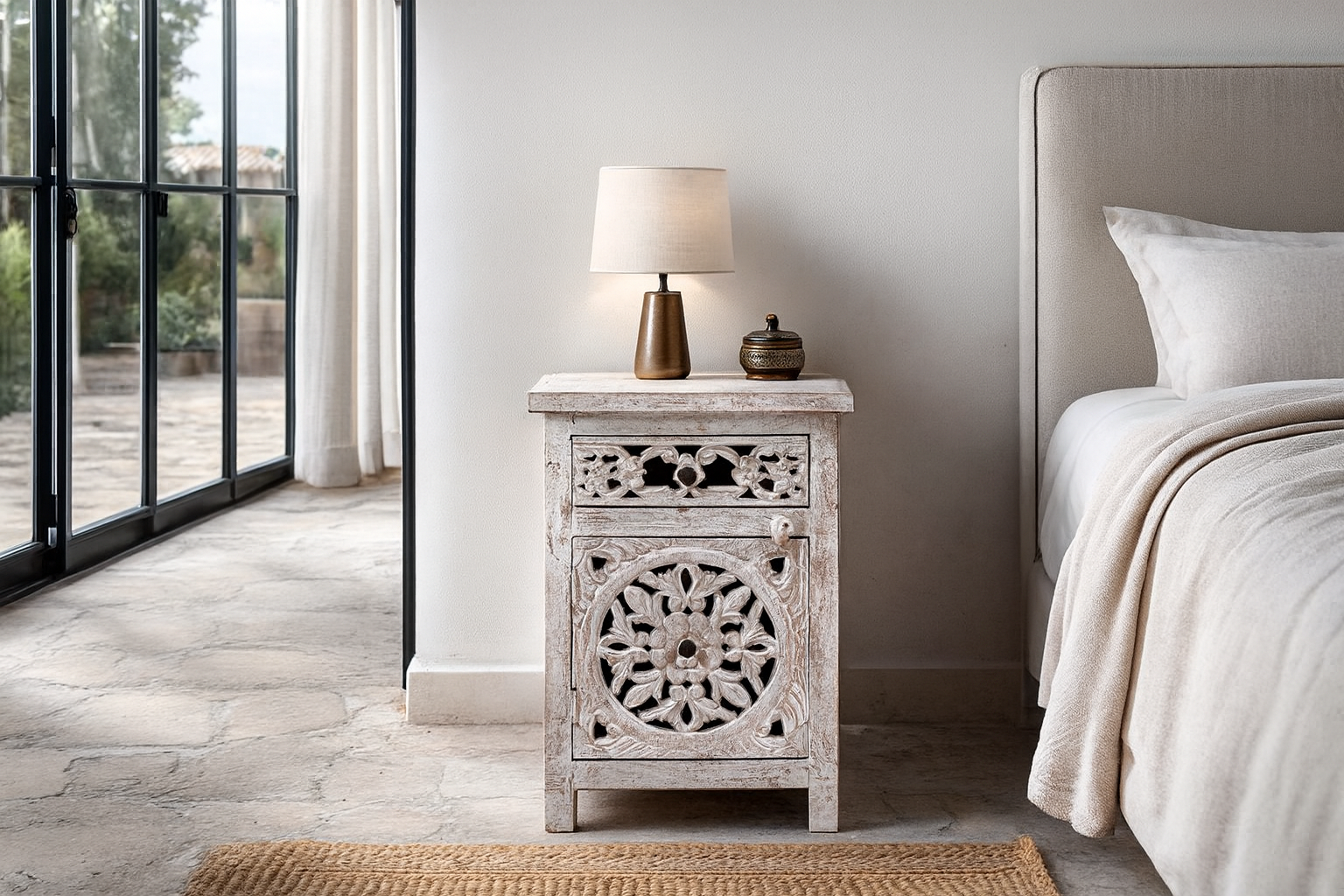 Lifestyle image with a Whitewashed nightstand made of mango wood with Mediterranean-style carved detailing and one drawer – Gagan bedside table by Om Home & Garden