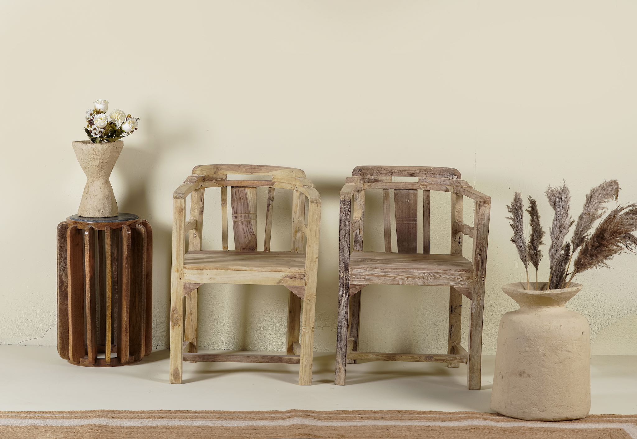 Rustic-style armchair made from reclaimed teak wood, featuring a natural, unfinished look with visible wood grain and variations in tone, and a curved backrest with vertical slats.