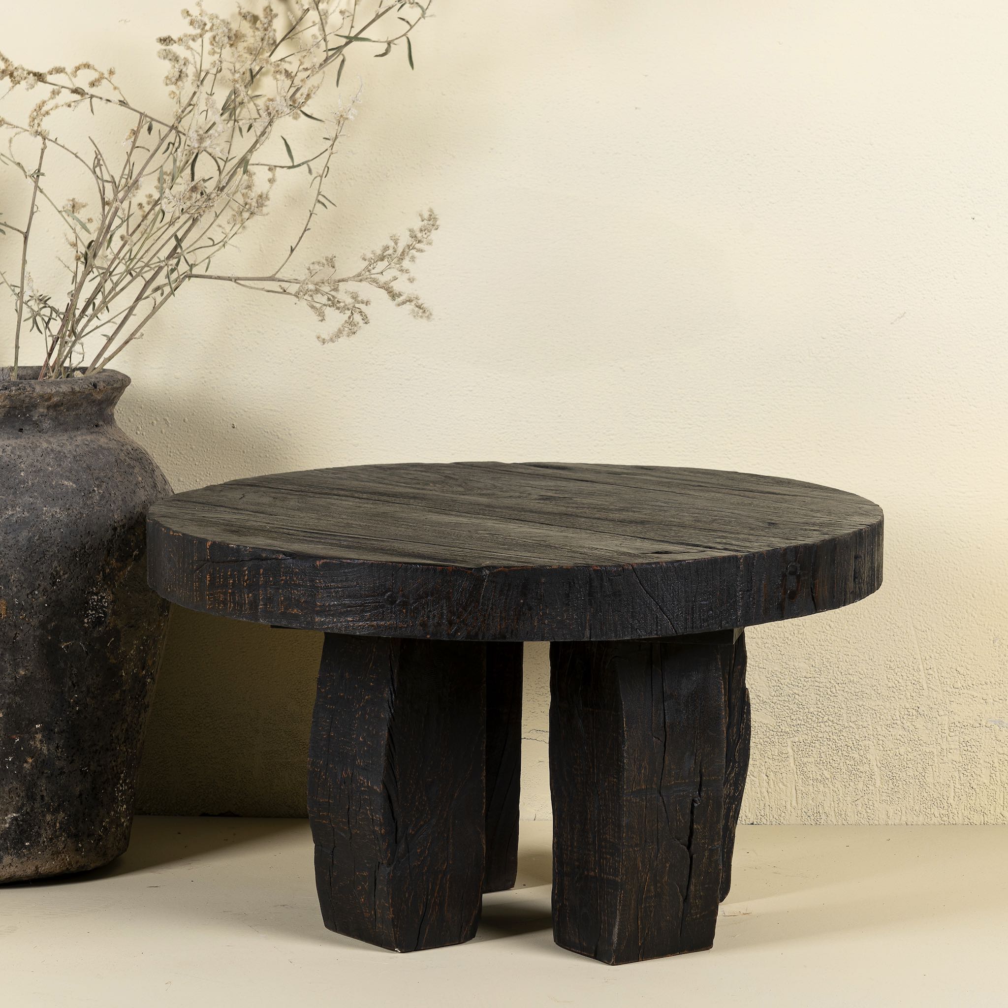 Front view of a rustic wood coffee table with round reclaimed teak top and black charred finish; sustainable furniture, 70 cm diameter, 40 cm height.