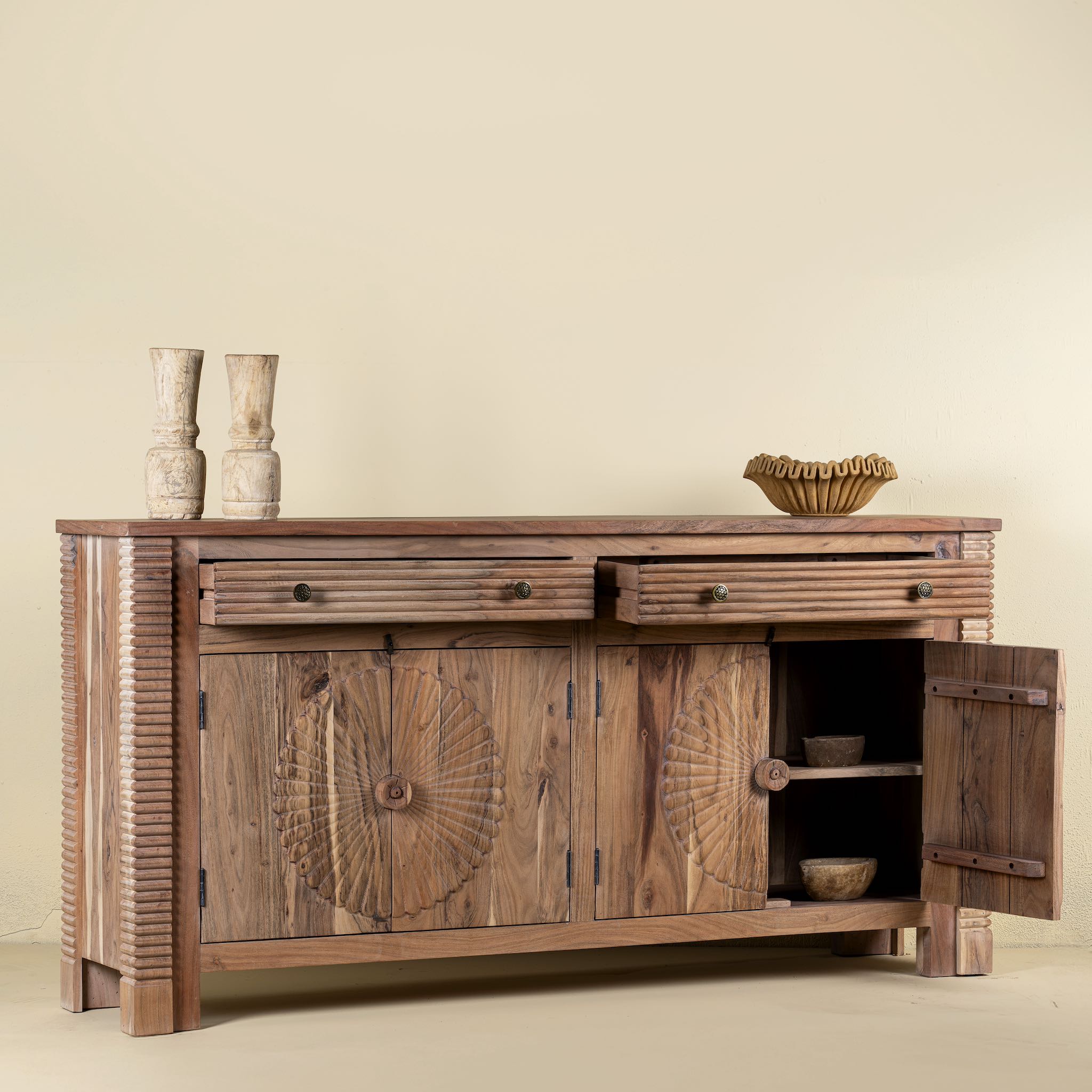 Open door picture of a carved acacia wood sideboard with four doors, two drawers, brass handles, and tapered legs; artisanal acacia wood furniture, 180 × 40 × 90 cm.