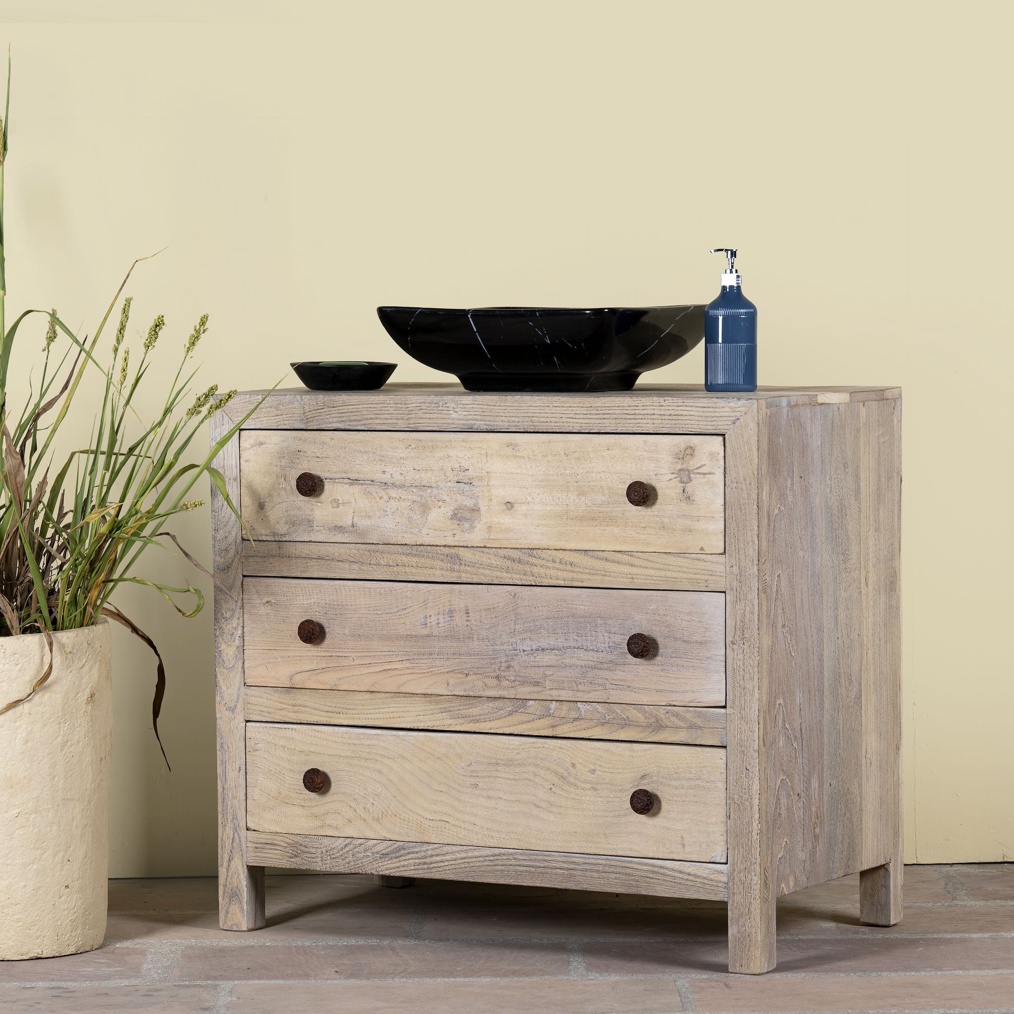 Side angle image of a reclaimed wood chest of 3 drawers with rustic finish and round knobs; Ibiza style sustainable furniture, 90 × 50 × 80 cm.