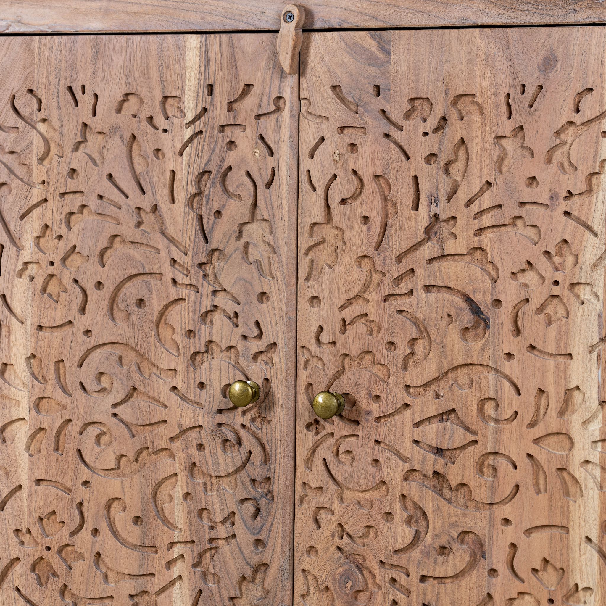 Close up image of a carved acacia wood cupboard with floral cutout doors and brass knobs, 90 × 40 × 90 cm.