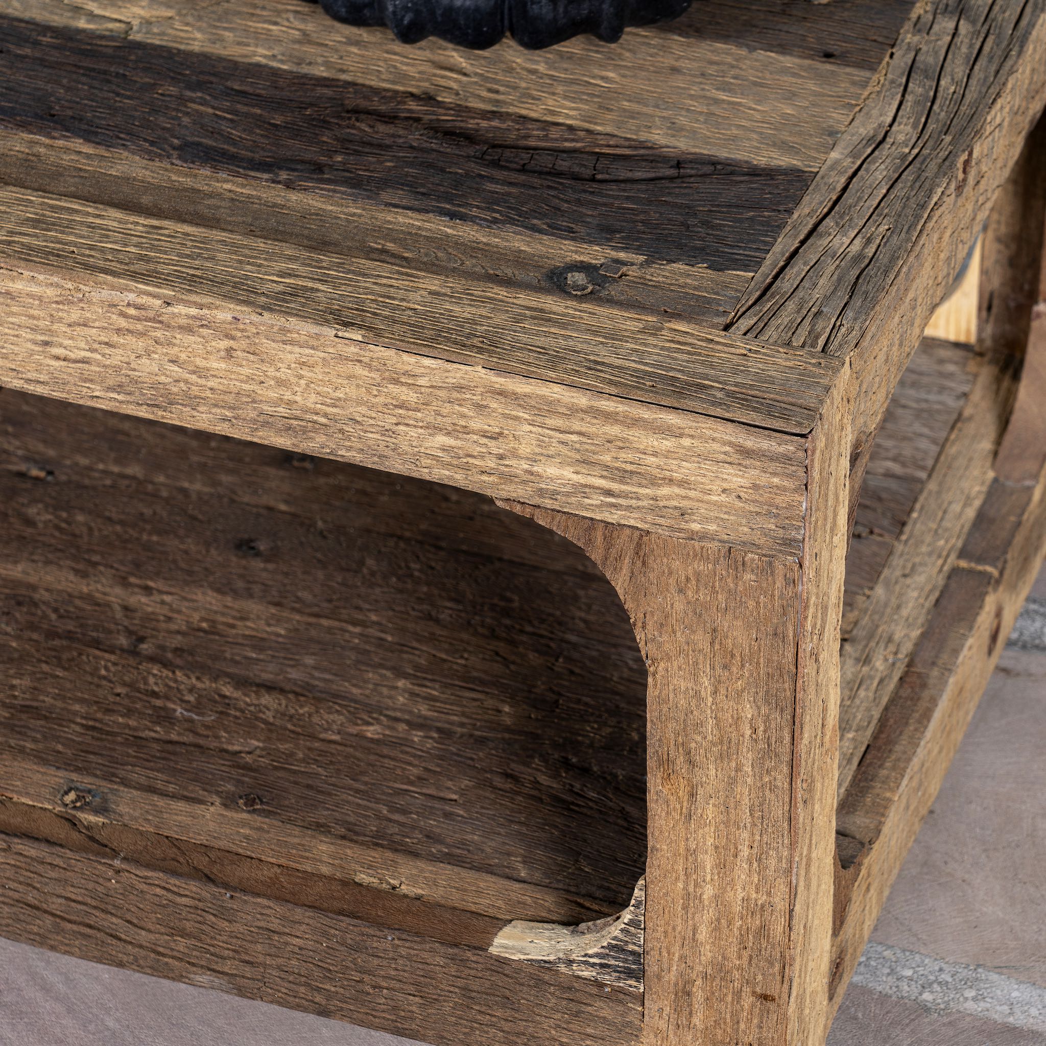Close up view of a driftwood coffee table made from reclaimed wood with rustic finish and open lower shelf; sustainable furniture, 120 × 60 × 40 cm.