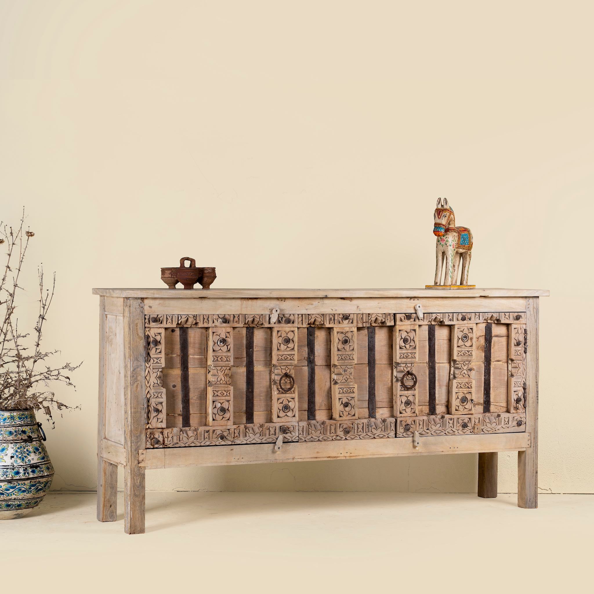 Side angle view of a console table made from old teak door panels, featuring traditional hand-carved details, iron ring accents, and built-in storage in a natural rustic finish.