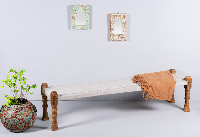 Side angle image of a low mango wood bench with handwoven cotton seat and hand-carved recycled wood frame; 180 × 45 × 20 cm.