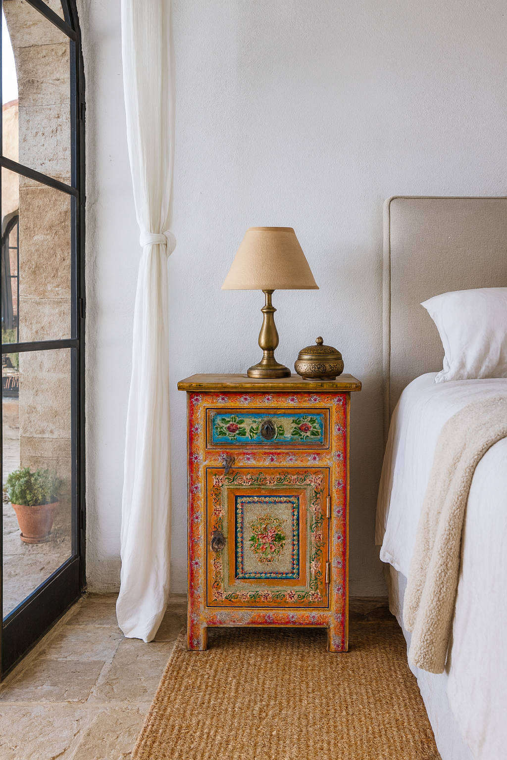 Lifestyle scene of a set of two hand painted bedside tables with floral motifs; sustainable furniture made of recycled wood, 45 × 35 × 70 cm.
