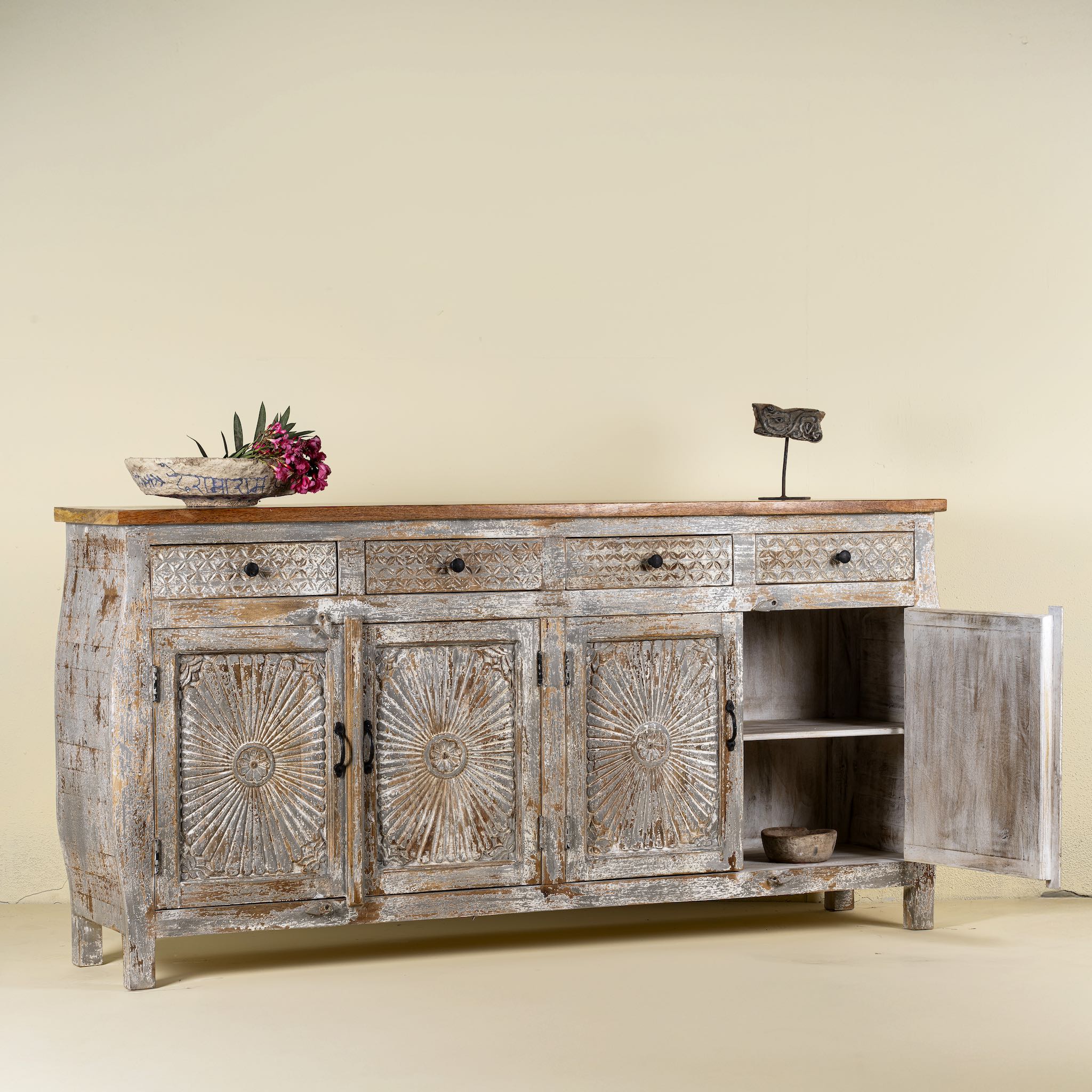 Open door view of a hand carved Mango wood sideboard with floral design, 4 doors and 4 drawers in vintage distressed look.