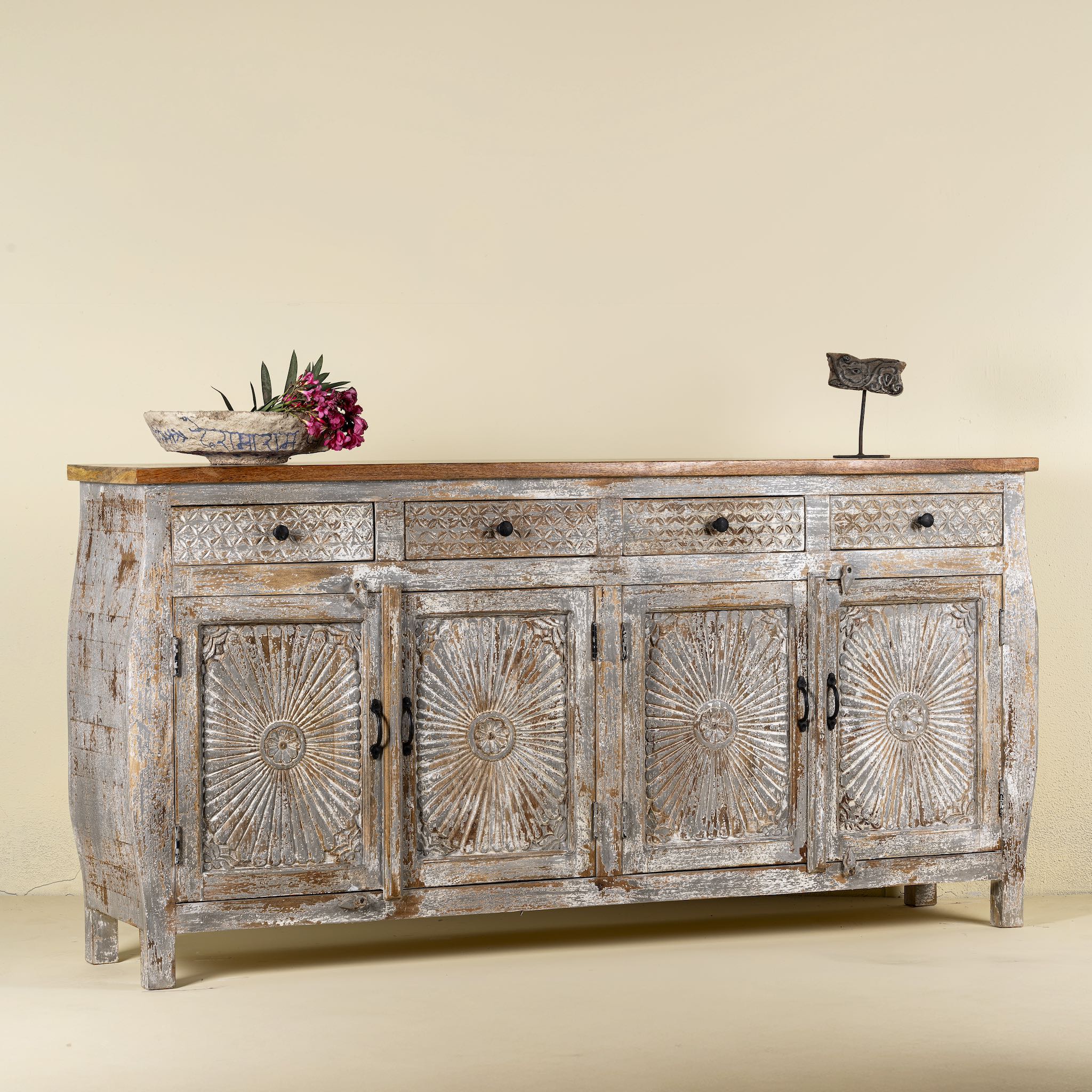 Side view of a hand carved Mango wood sideboard with floral design, 4 doors and 4 drawers in vintage distressed look.