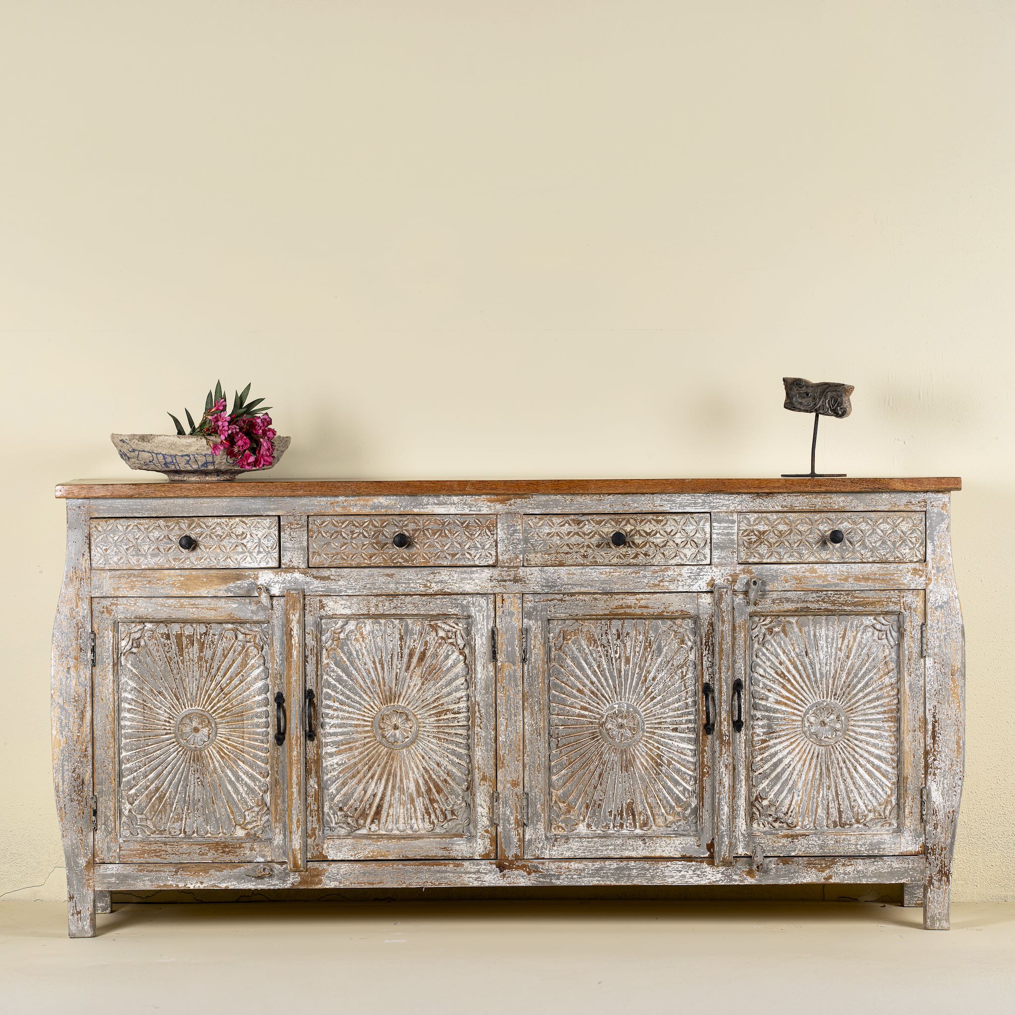 Front view of a hand carved Mango wood sideboard with floral design, 4 doors and 4 drawers in vintage distressed look.