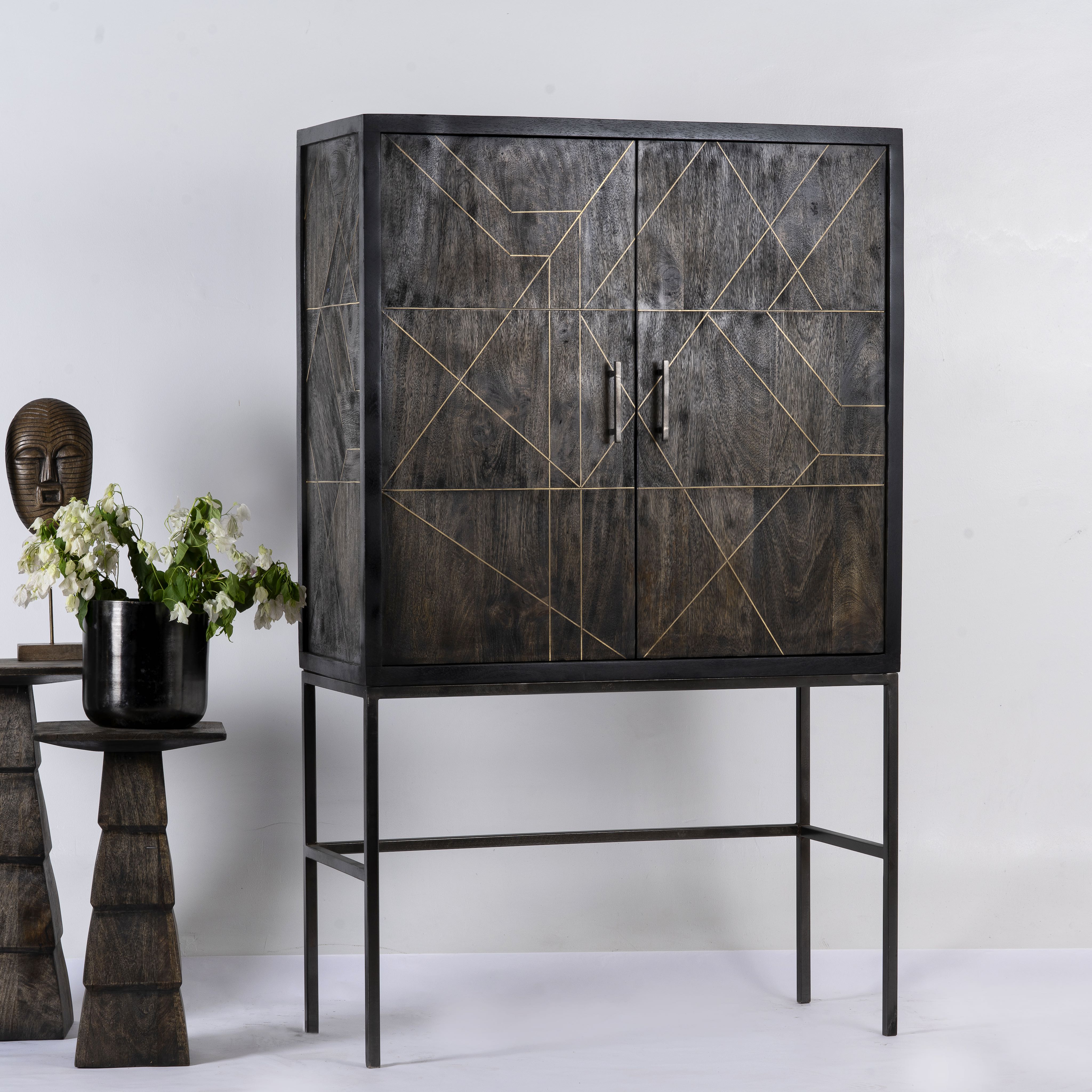 Side angle image of a black wooden cabinet with handcrafted copper inlays and nickel-plated metal base—an artisanal furniture piece with a refined minimalistic style.
