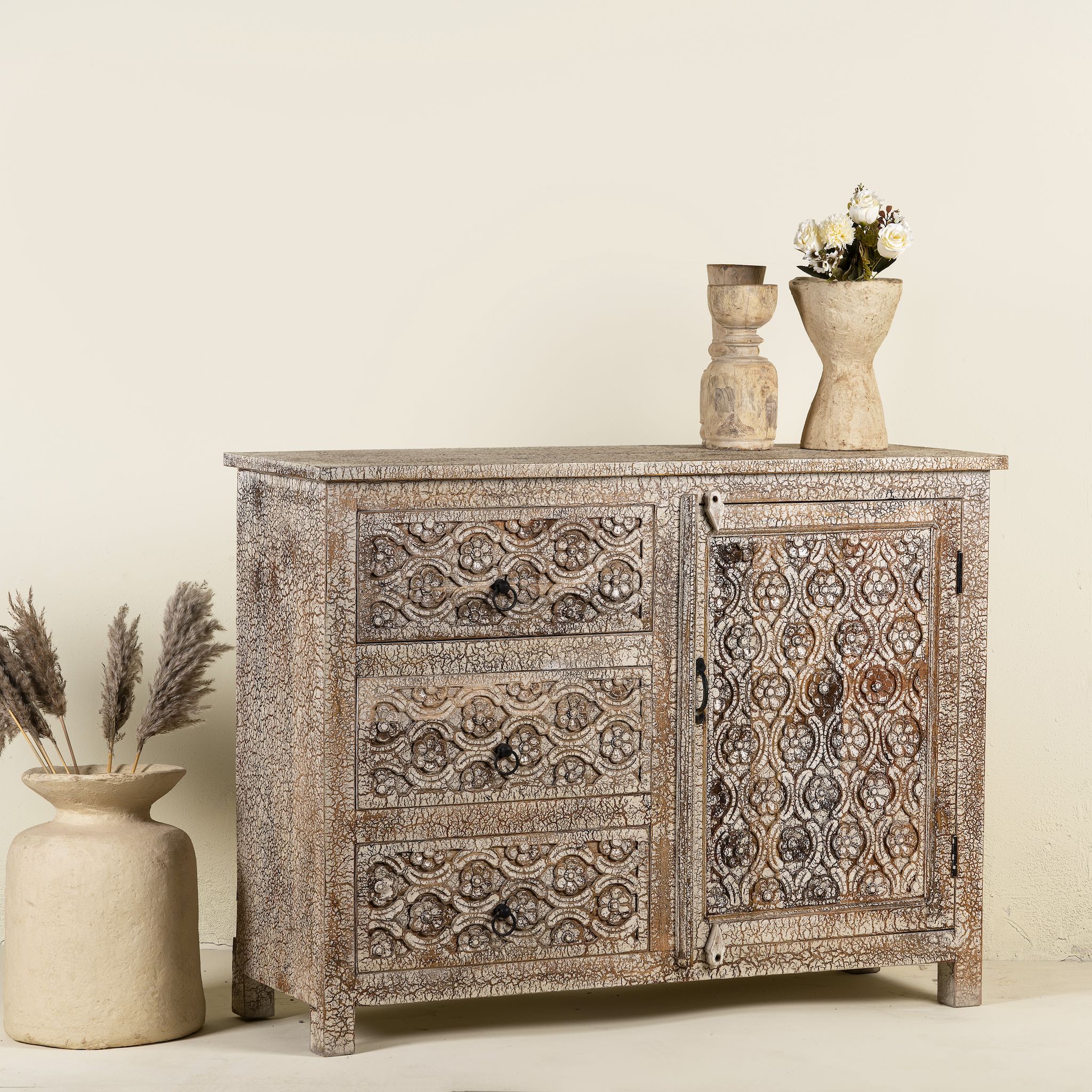 Side angle image of a hand-carved sideboard in mango wood furniture style with two doors, three drawers, and vintage three-layer finish.