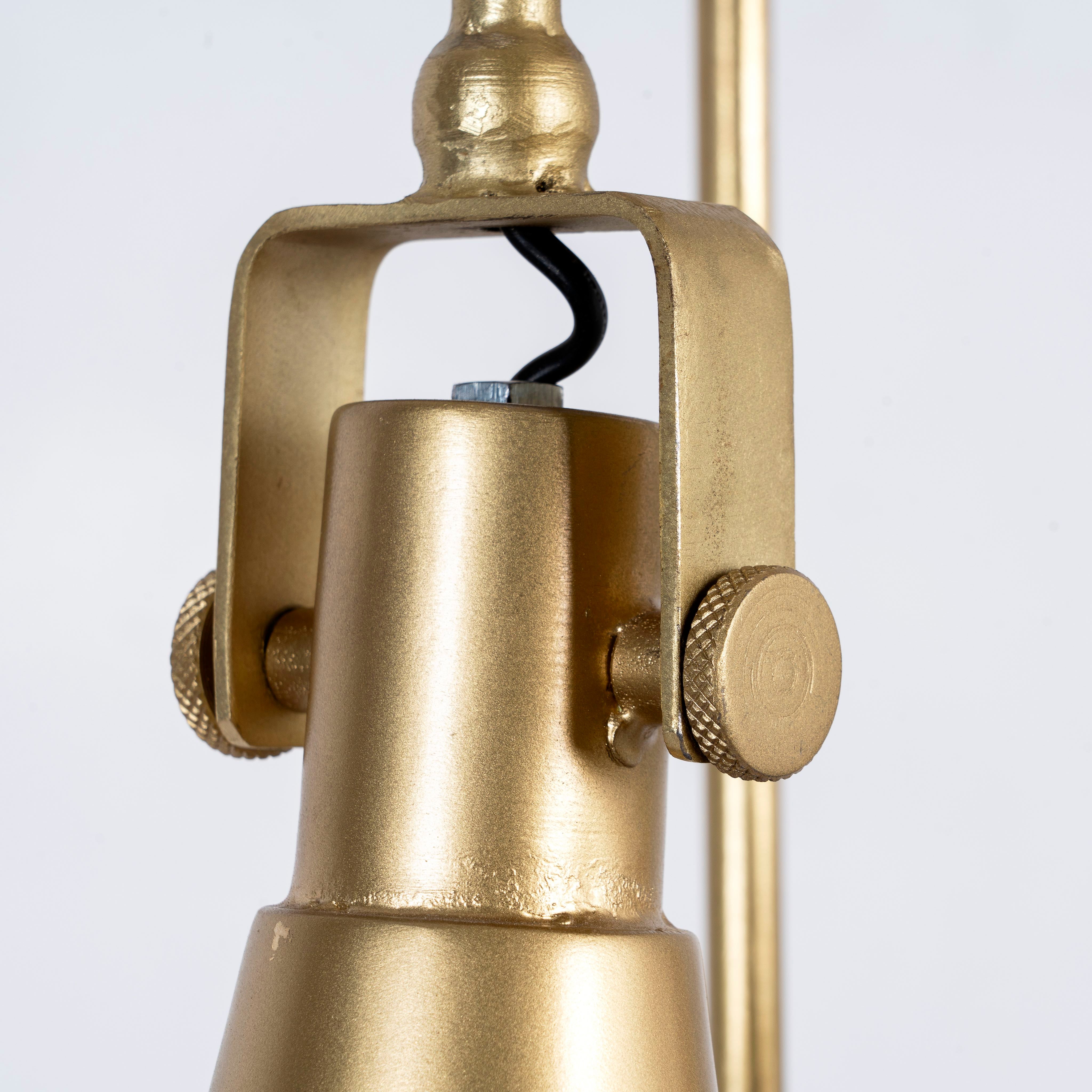 Close up image of a polished brass iron pendant lamp with sleek tapered shape – minimalistic style lighting fixture with three lights for kitchens, dining rooms, or entryways.