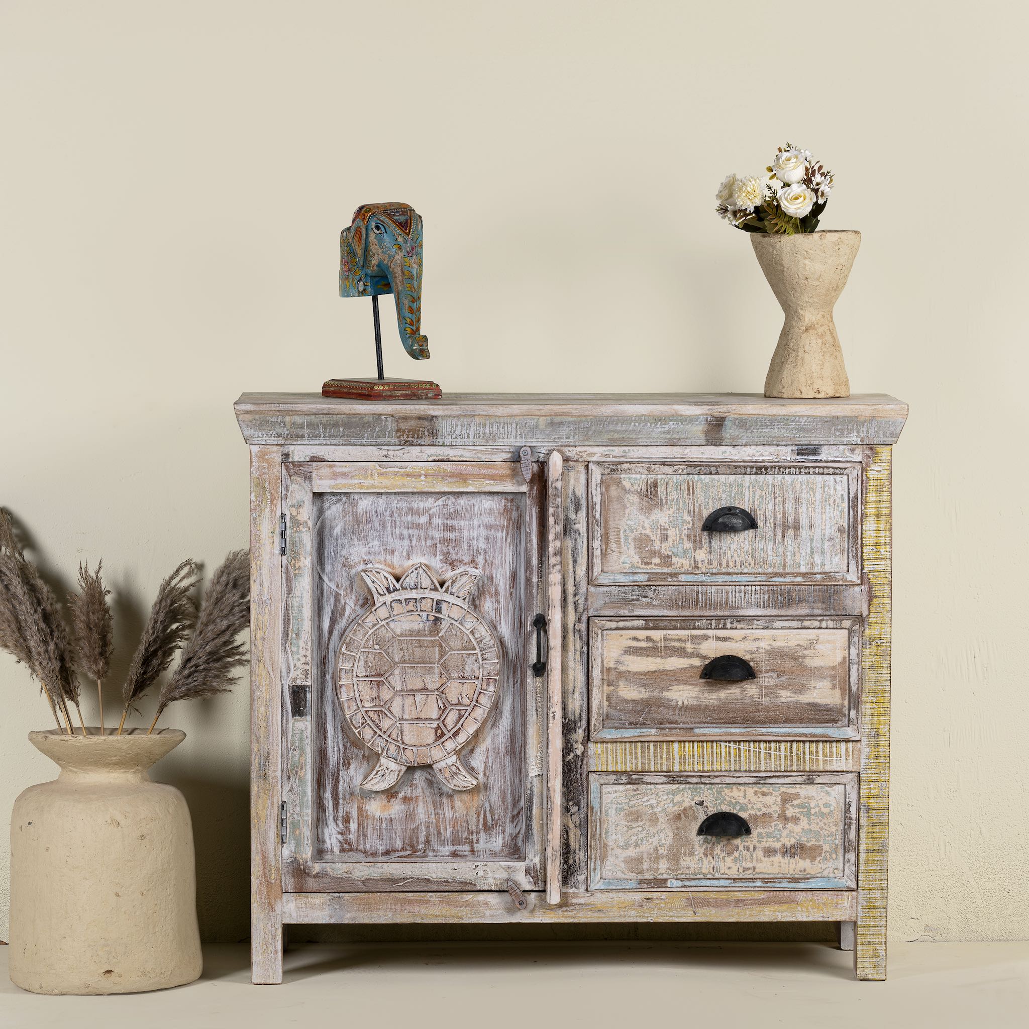 Handcrafted reclaimed wood cupboard with a turtle design, featuring one door and three drawers, placed against a neutral background with decorative items on top.
