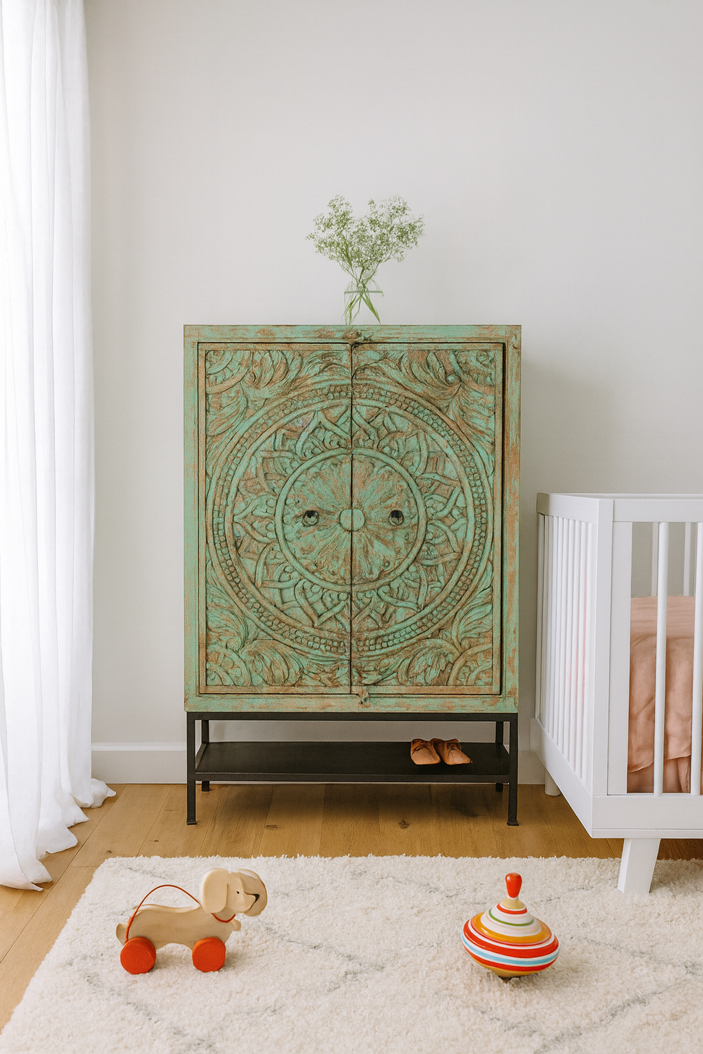 Lifestyle imagination of a carved mango wood cabinet with floral hand-carving, distressed green finish, iron stand, 100 × 40 × 150 cm.