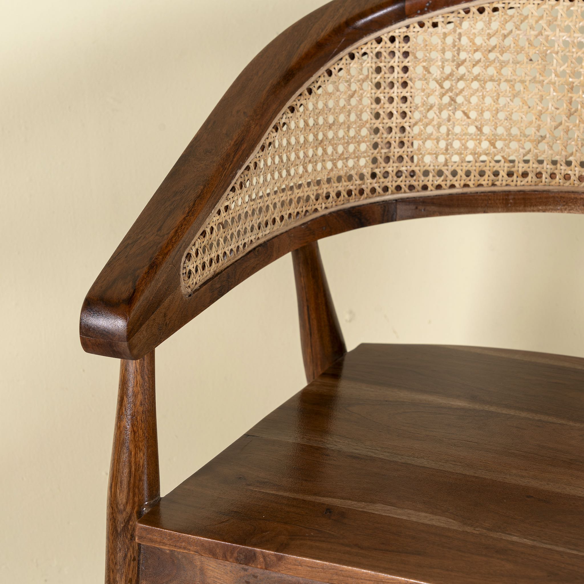 Close up image of an acacia wood chair with curved frame and woven rattan backrest, elegant wooden armchair, 60 × 45 × 90 cm.