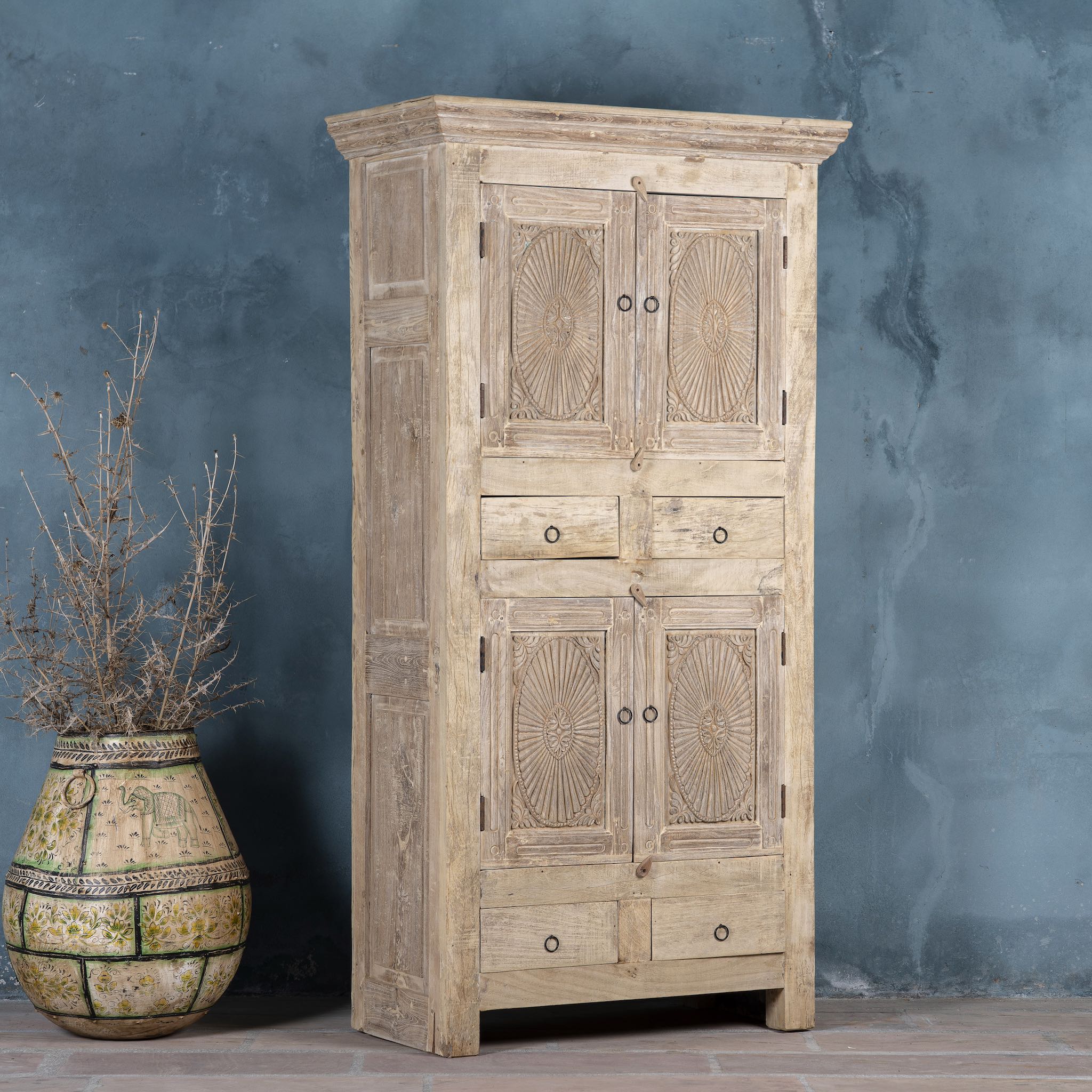 Side angle image of a handcrafted wooden carved wardrobe with antique panel doors – teak wood furniture with rustic charm and traditional detailing.