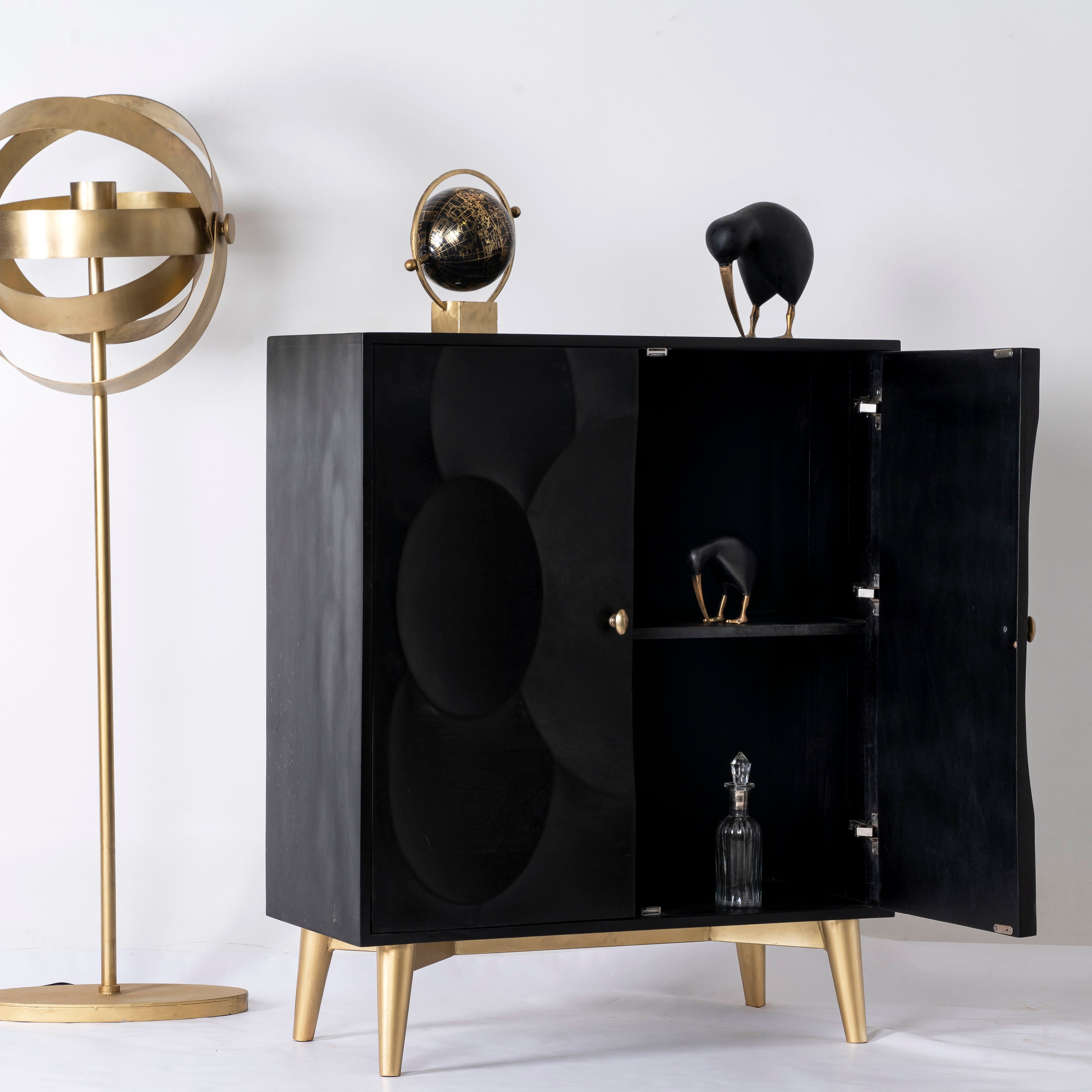 Side angle image with open doors of a black mango wood cabinet with carved circular patterns and brass-plated iron base, 91 × 43 × 111 cm.