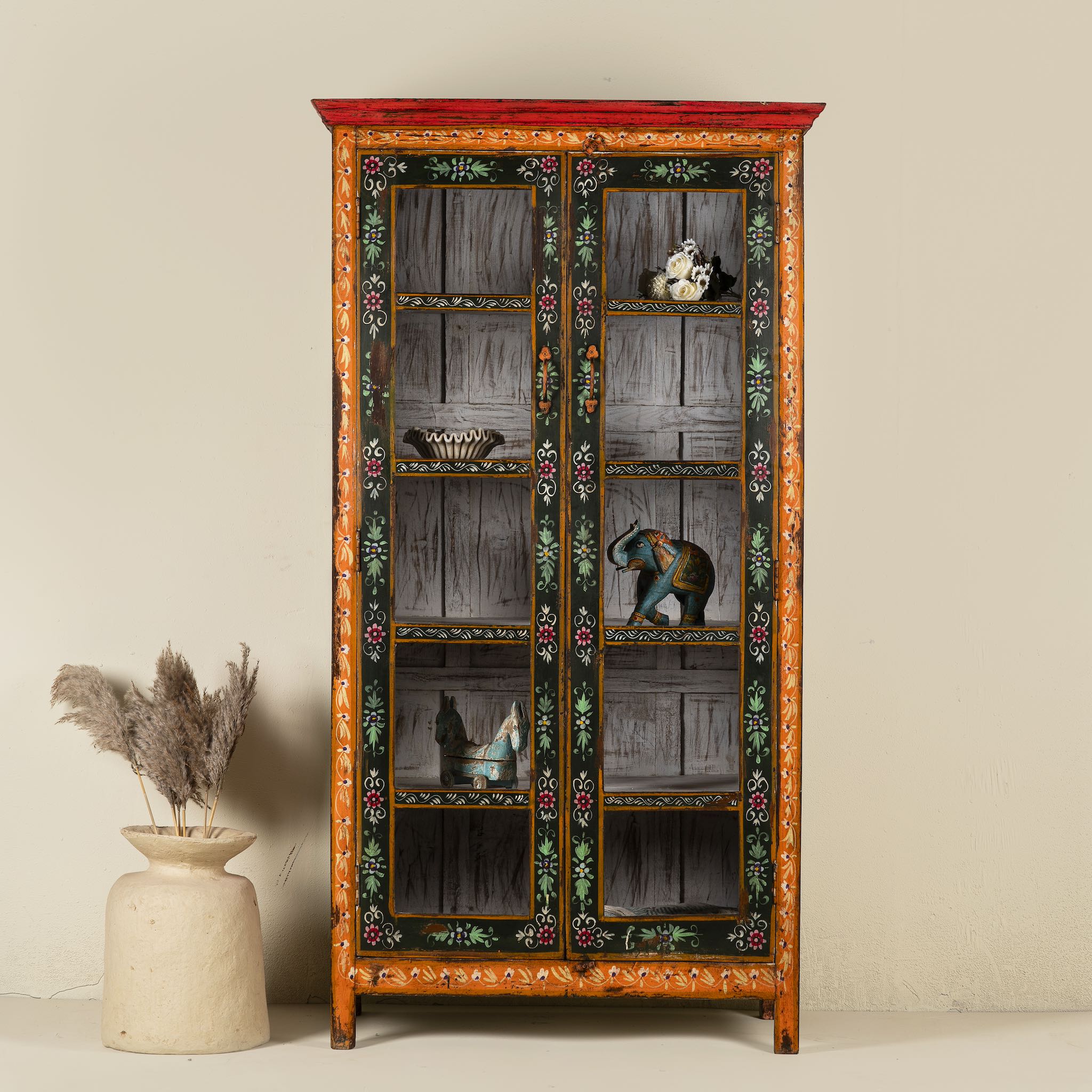A vintage style hand-painted reclaimed wood showcase with floral motifs, featuring four compartments and a vibrant red door.