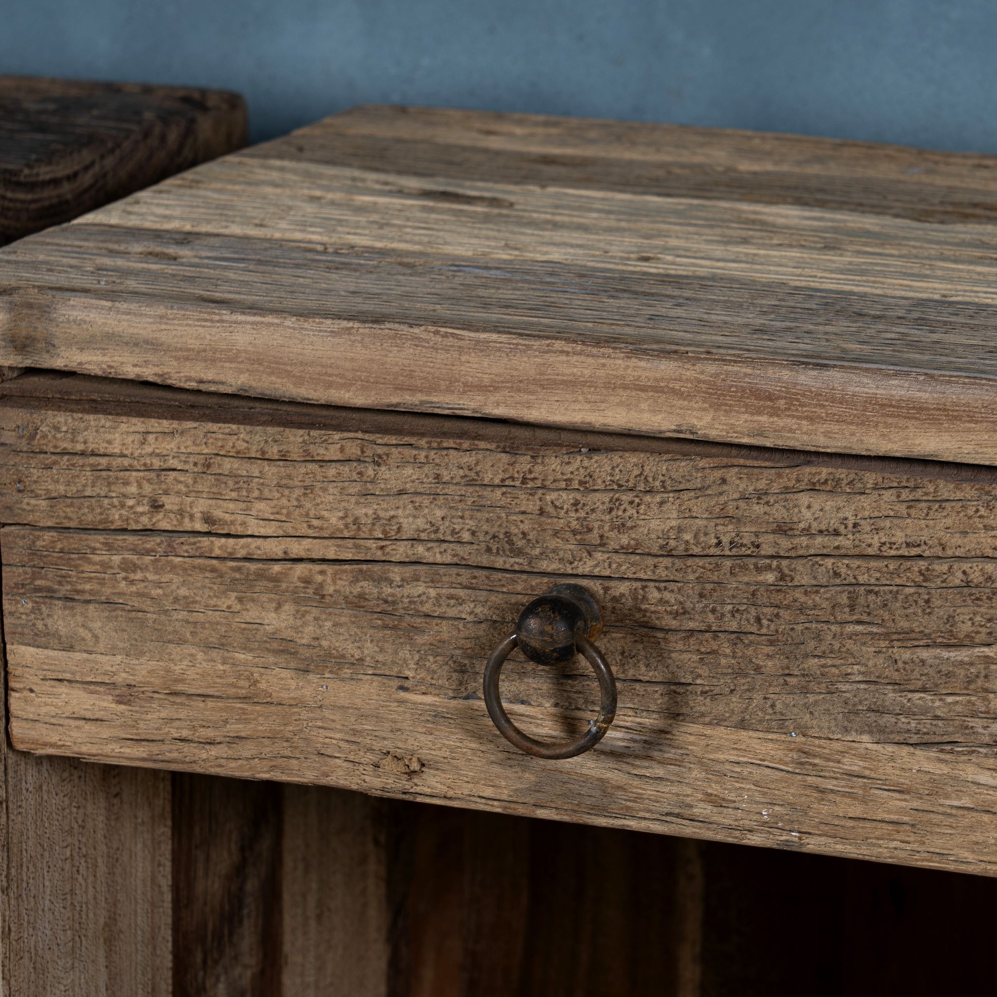 Close up image of a reclaimed wood bedside table with drawer and open shelf – handcrafted driftwood furniture designed for rustic minimalism and natural interiors.