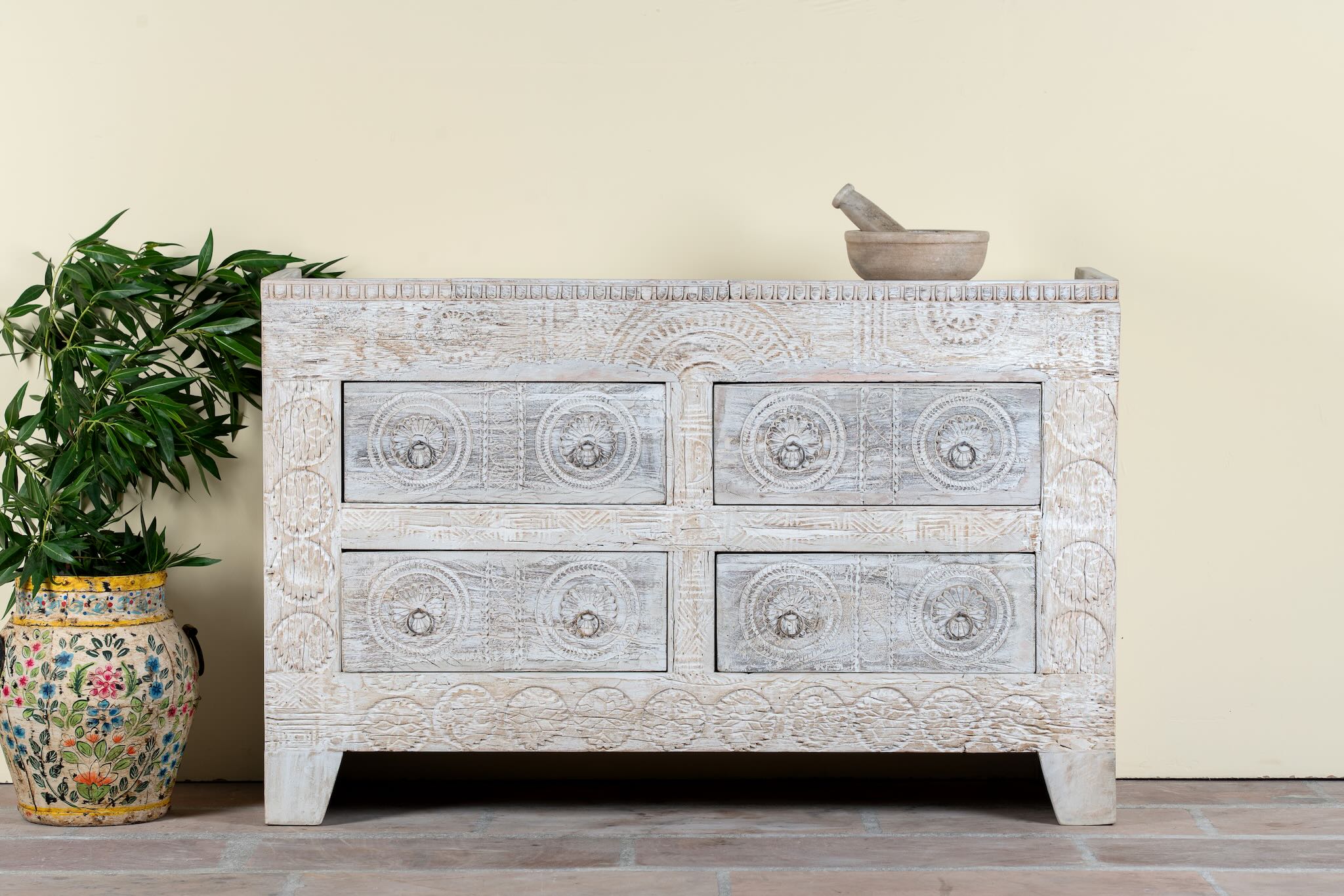 Handcrafted chest of drawers Zuber made from reclaimed wood, featuring four carved drawers with circular motifs and a whitewashed finish. A rustic, sustainable furniture piece with soft texture and elegant detailing.
