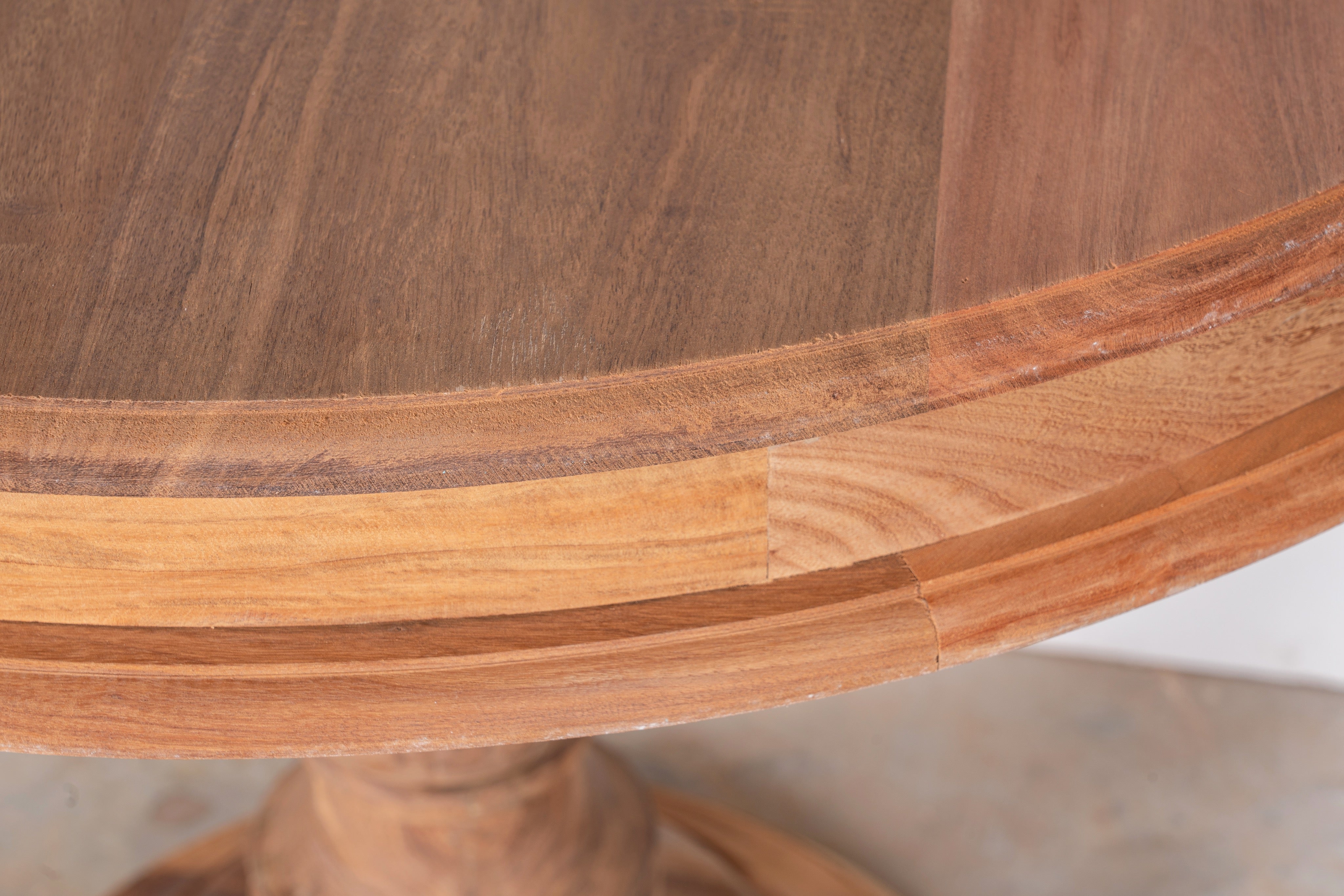 Close up image of a round solid wood dining table made from reclaimed teak with carved pedestal base; rustic reclaimed teak wood dining table, 100 cm diameter × 78 cm height.
