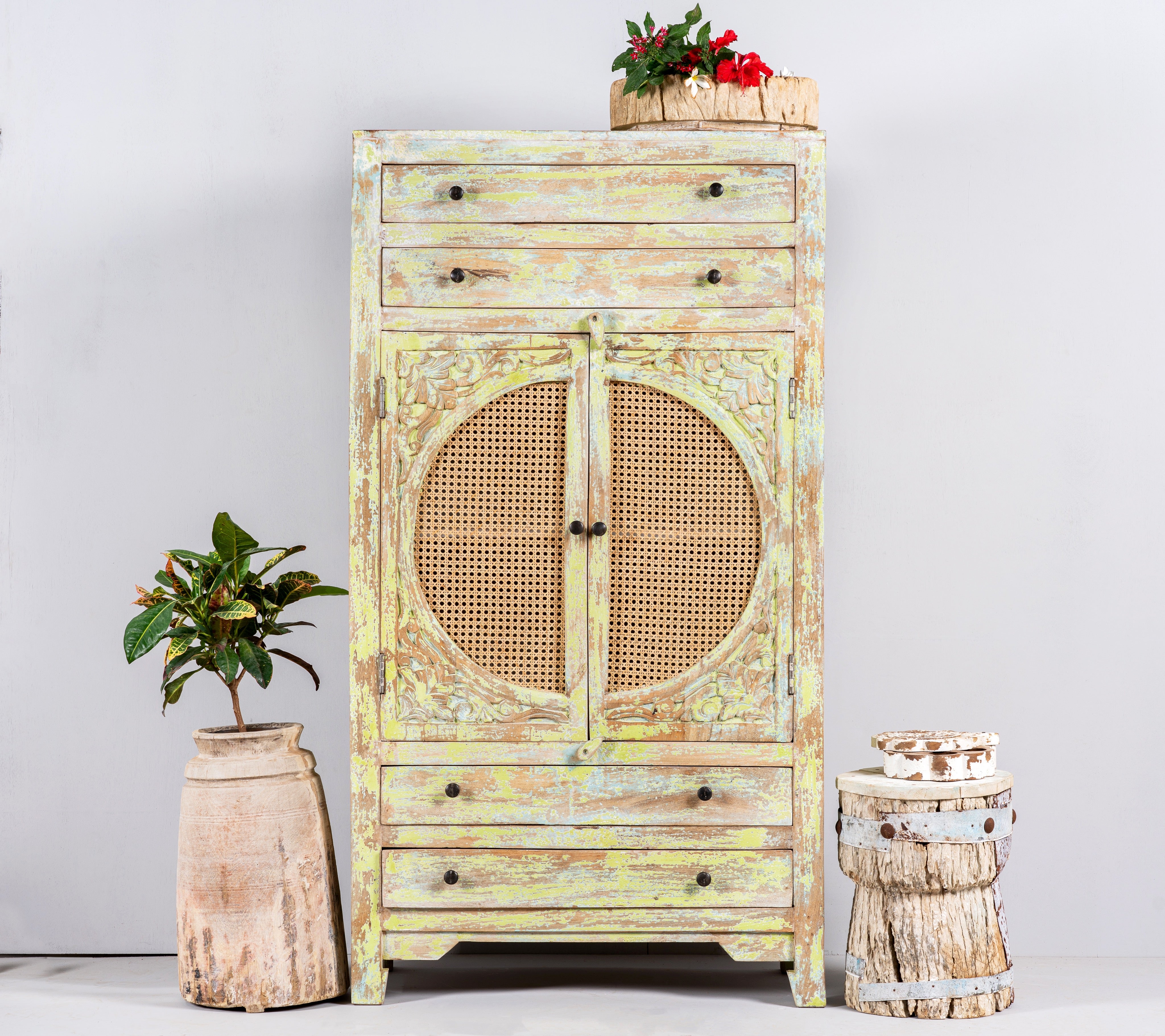 Lifestyle image of a green-washed mango wood cabinet with floral carvings, rattan door inserts, versatile living room furniture, 80 × 148 × 40 cm.