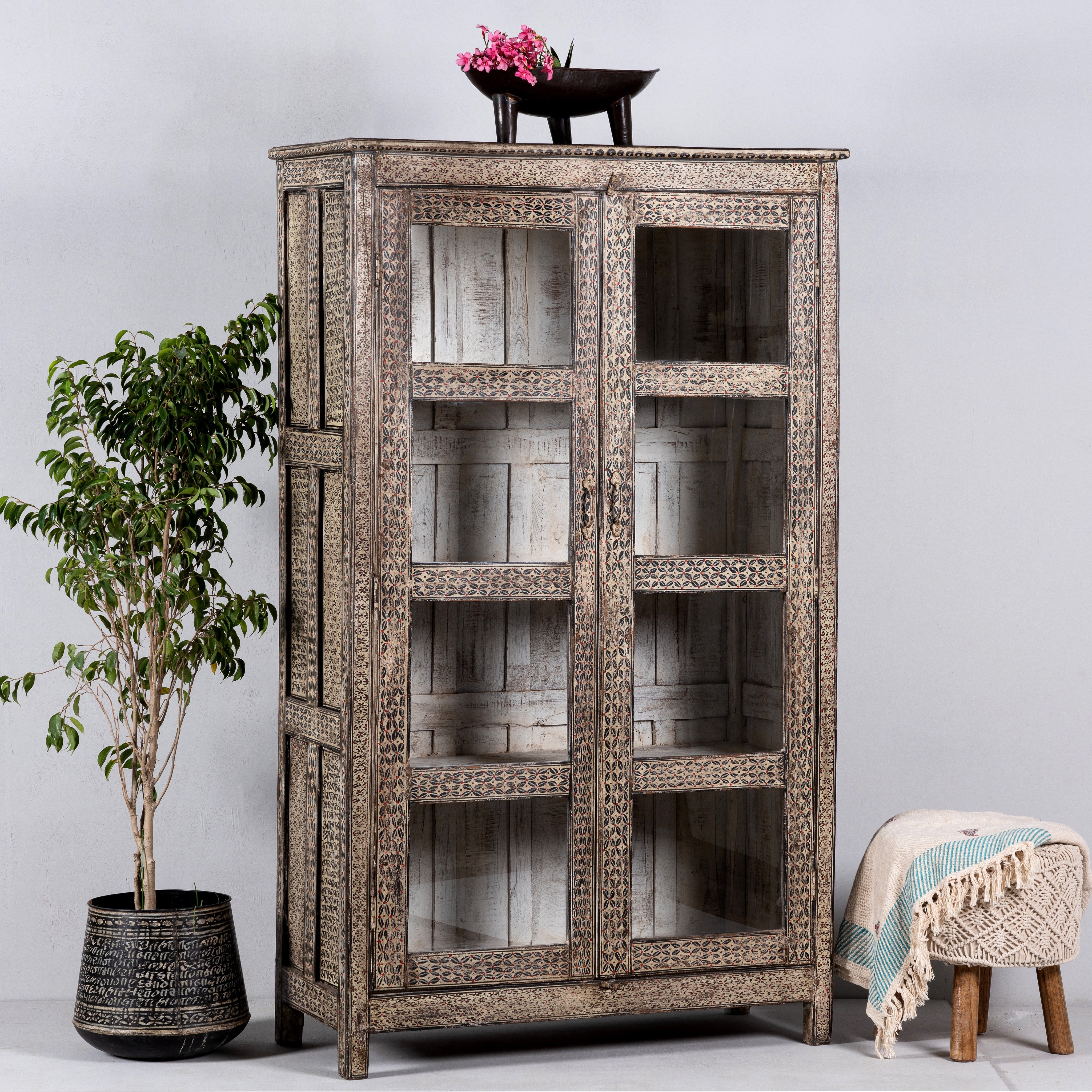 Side angle image of a handcrafted reclaimed teak wood display cabinet with glass doors and hand-painted Sanskrit symbols – sustainable furniture with vintage soul and artisanal charm.
