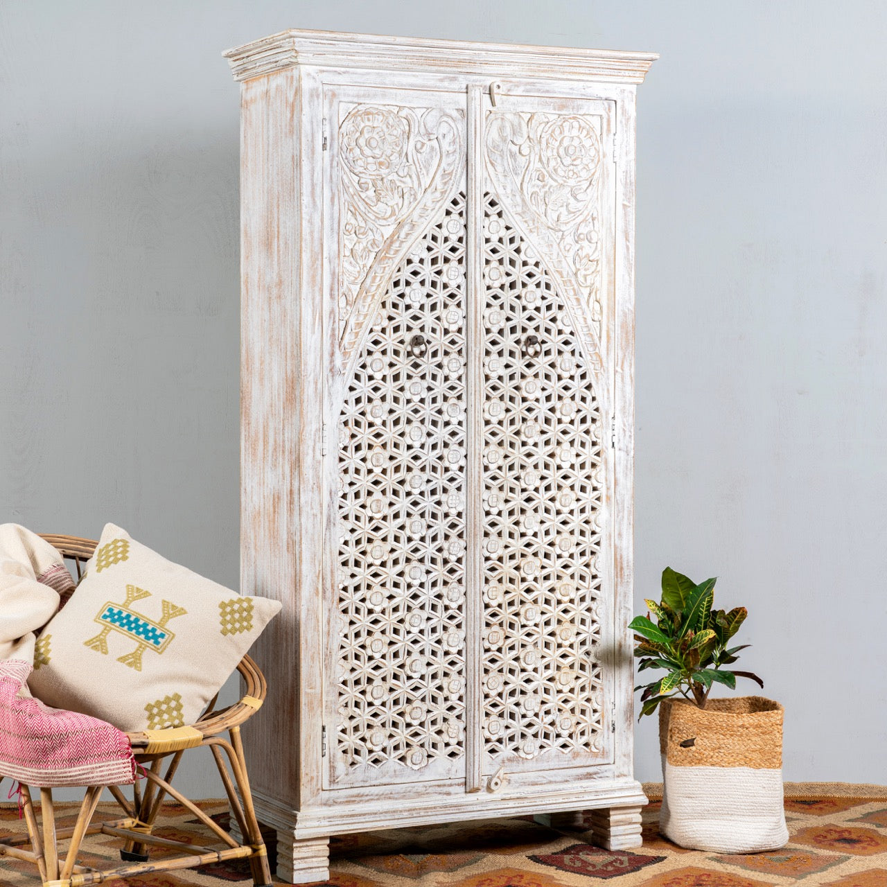 Side angle image of a white-washed hand-carved wooden wardrobe made of solid mango wood, vintage furniture with Mediterranean Ibiza style, 180 × 90 × 40 cm.