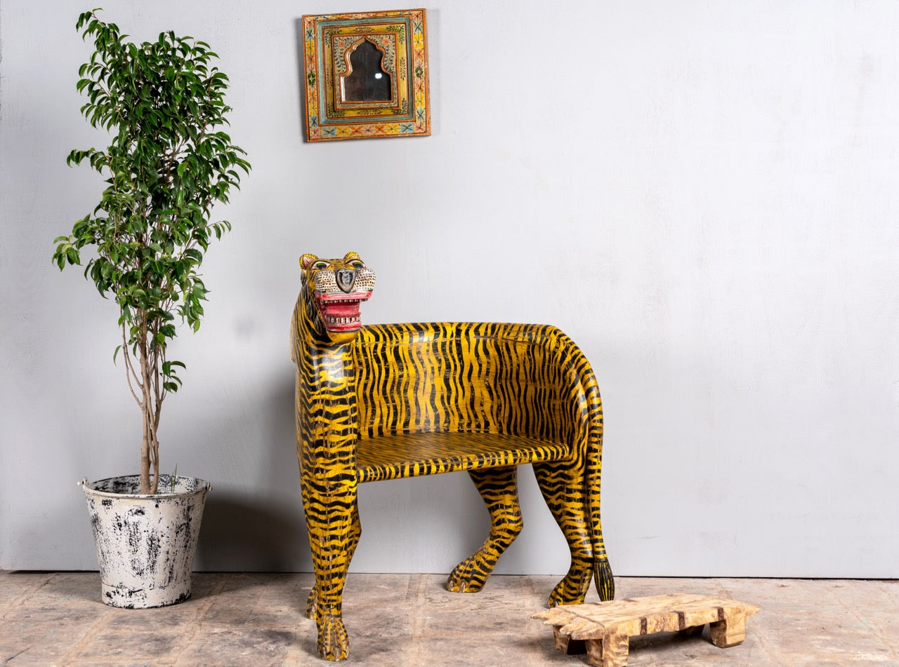 Image in side angle position of a hand-painted tiger chair made from recycled teak wood with carved tiger motif; ideal for a boho chic living room, 87 × 75 × 96 cm.