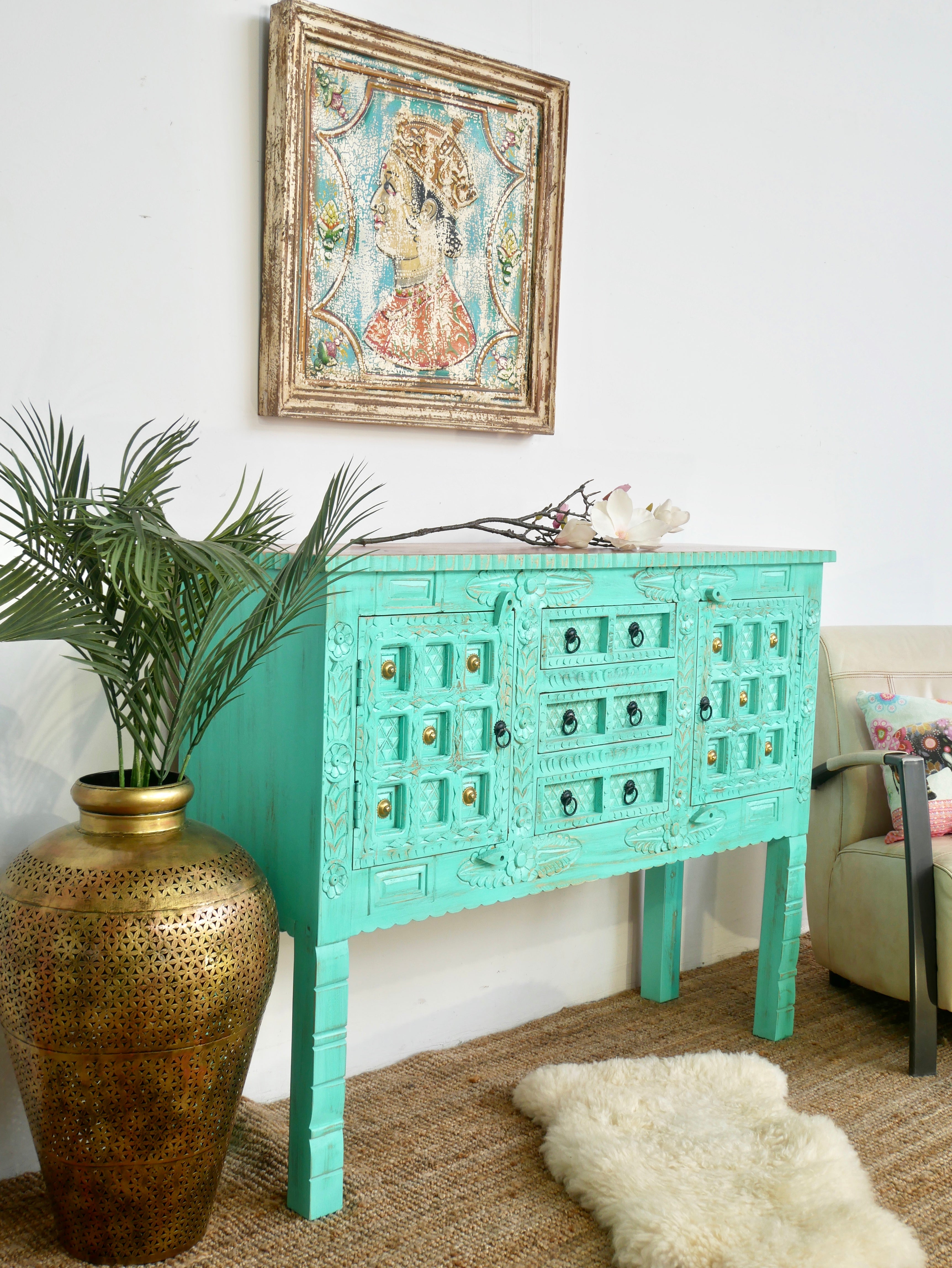 Side angle image of a green storage console table with carved mango wood doors and brass details; mango wood console table, 130 × 100 × 40 cm.