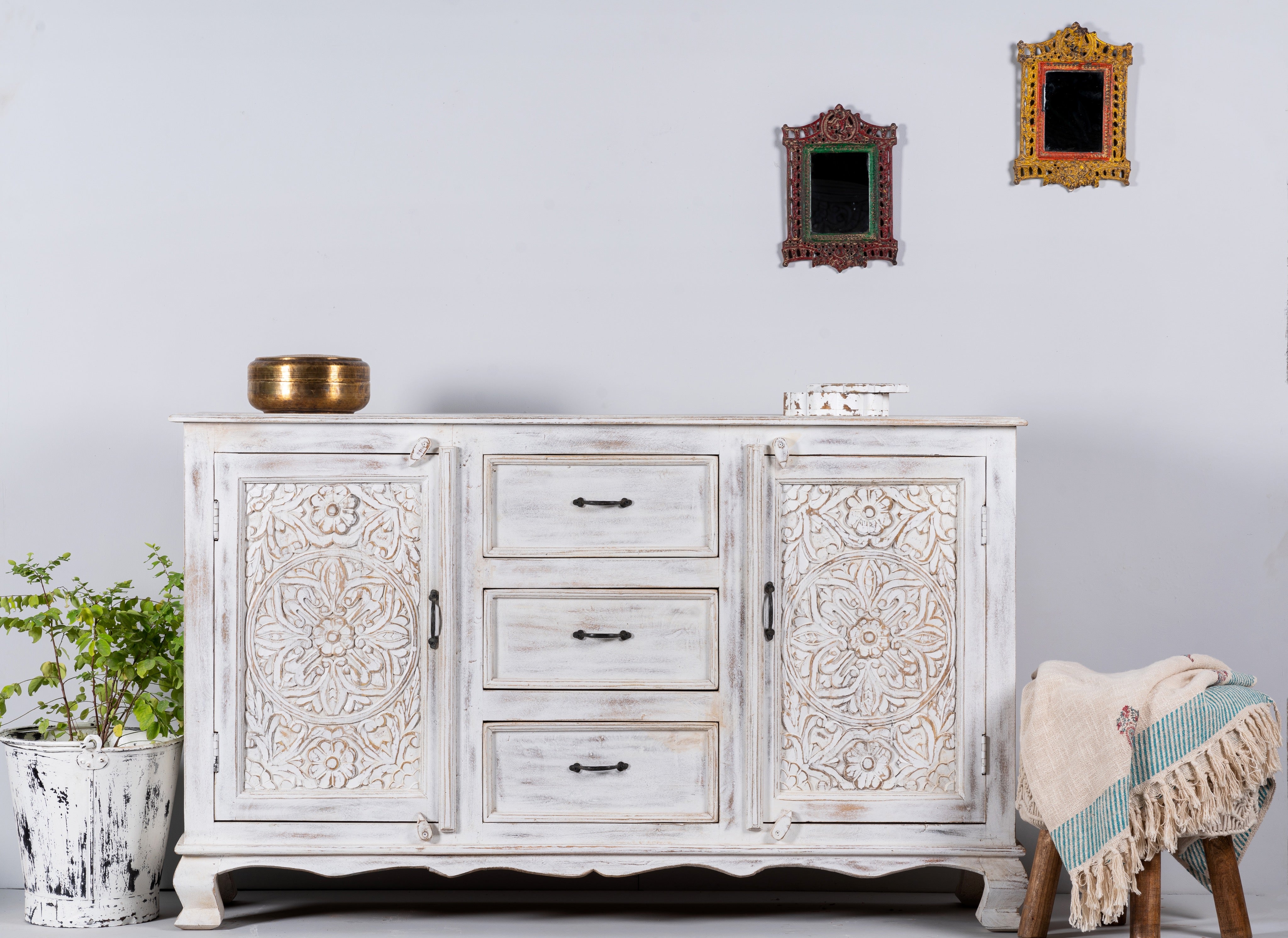 Lifestyle image of a mediterranean-style carved sideboard in solid mango wood with floral motifs and elegant legs; ideal for vintage home decor, 150 × 90 × 40 cm.