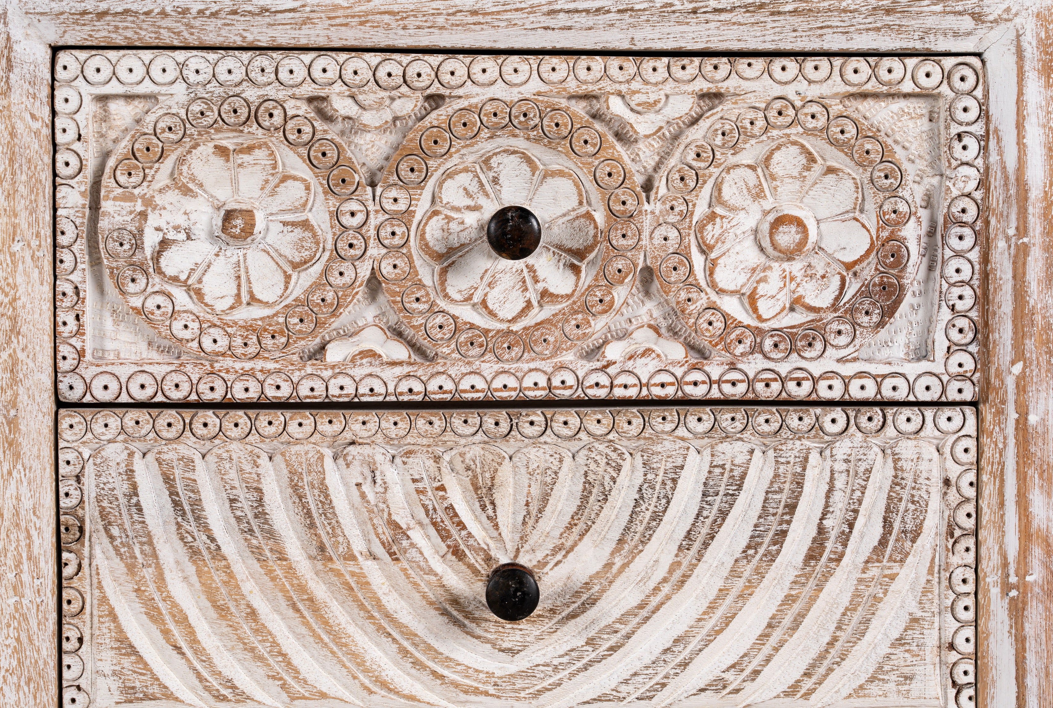 Close up image of a hand-carved mango wood sideboard with lotus-inspired drawer motifs and whitewashed finish; a wood carved sideboard and unique furniture piece, 160 × 92 × 45 cm.